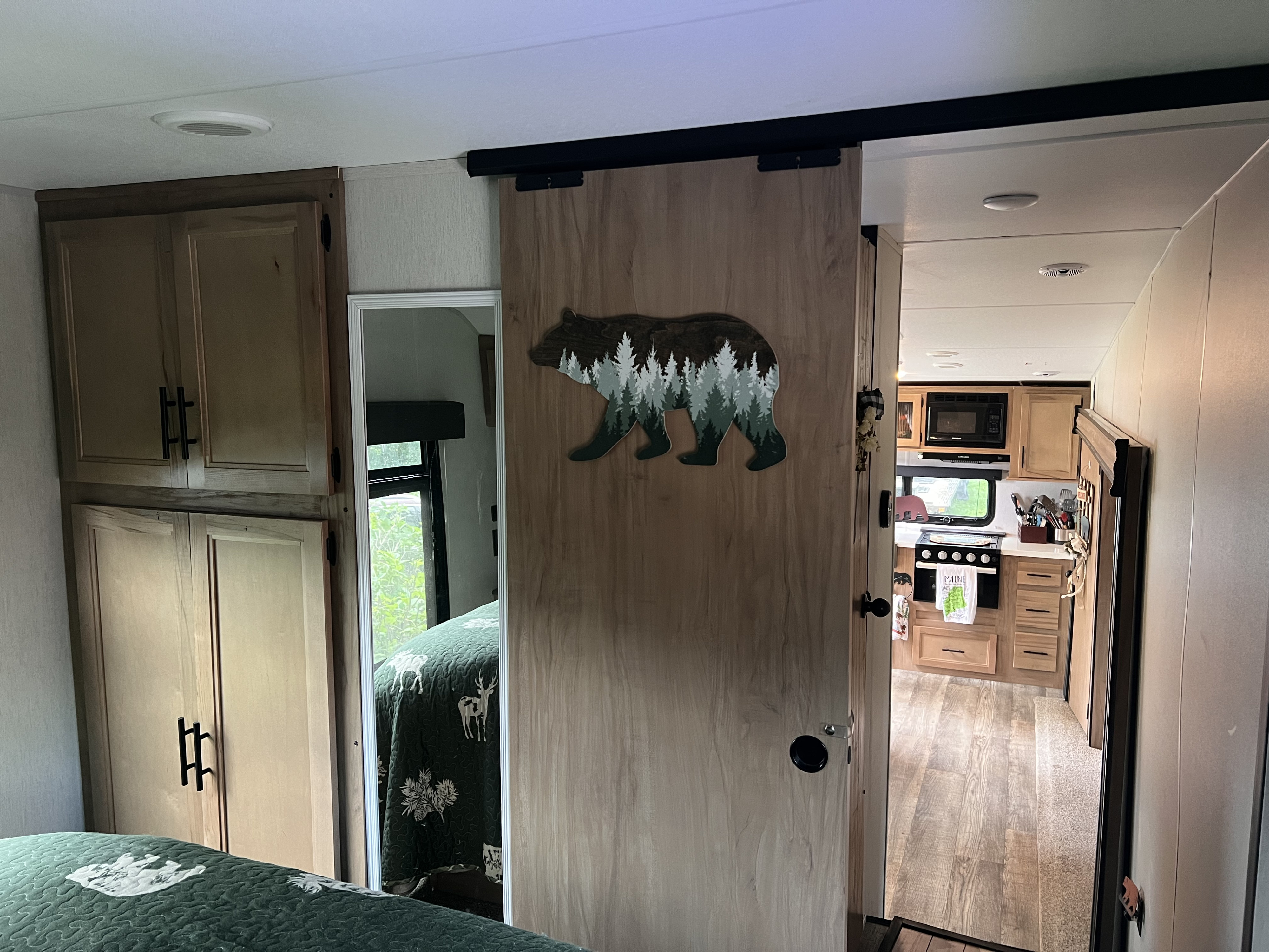 Explore this RV rental's cozy interior, featuring a bear-decorated sliding door connecting the bedroom to the kitchen area.. Forest River Cherokee Cherokee Black Label Series 2023