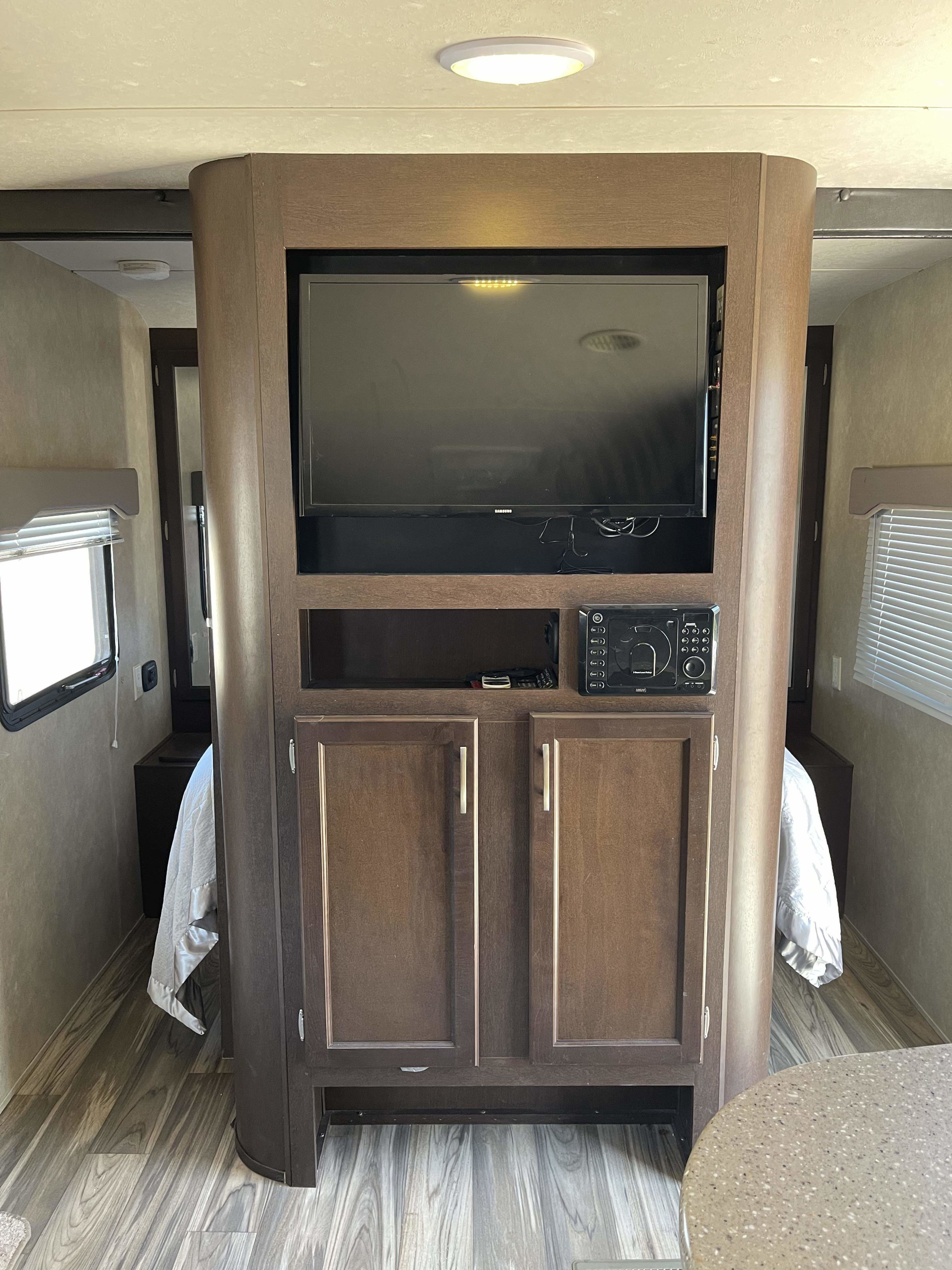 Inside this RV rental, a central entertainment unit with TV and stereo separates two cozy bedroom areas with windows.. Forest River T2850 2017