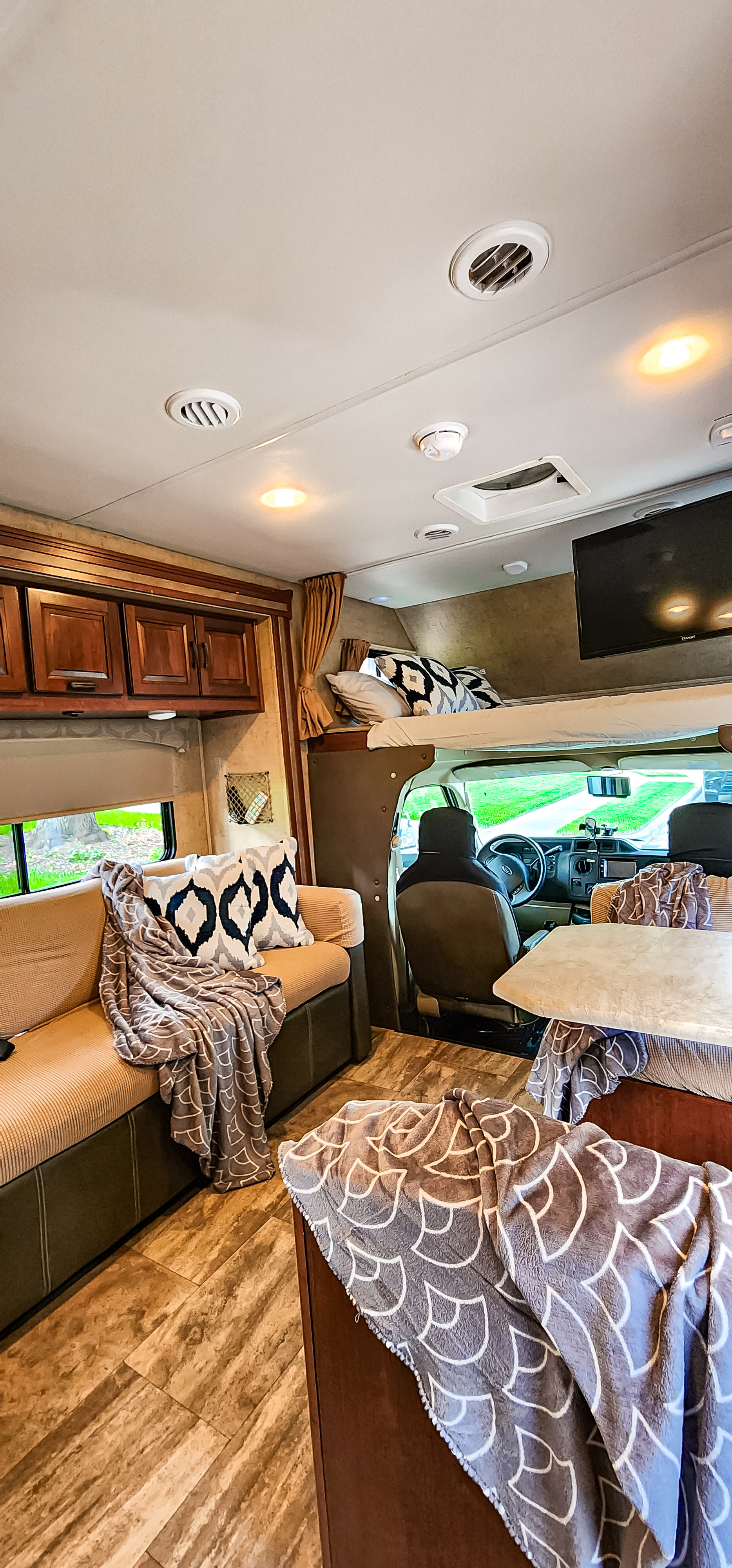 Spacious RV rental interior with a cozy couch, overhead bunk bed, dining area, and front cockpit. Ideal motorhome setup.. Forest River FORESTER 3171DS 2016