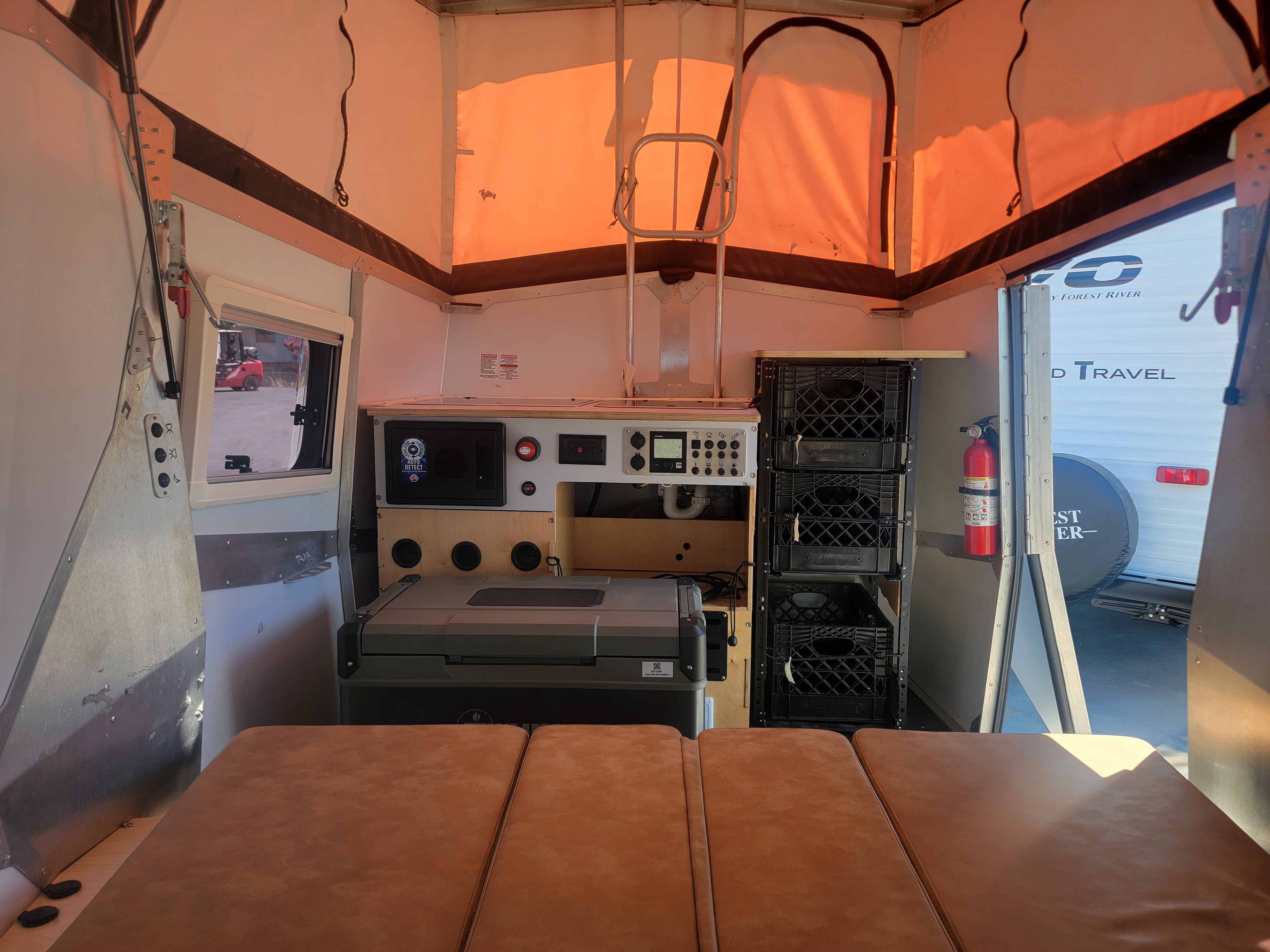 Interior of an RV rental: cozy pop-up camper with sleeping area, kitchen, and storage for your next adventure.. TAXA OUTDOORS CRICKET 2023