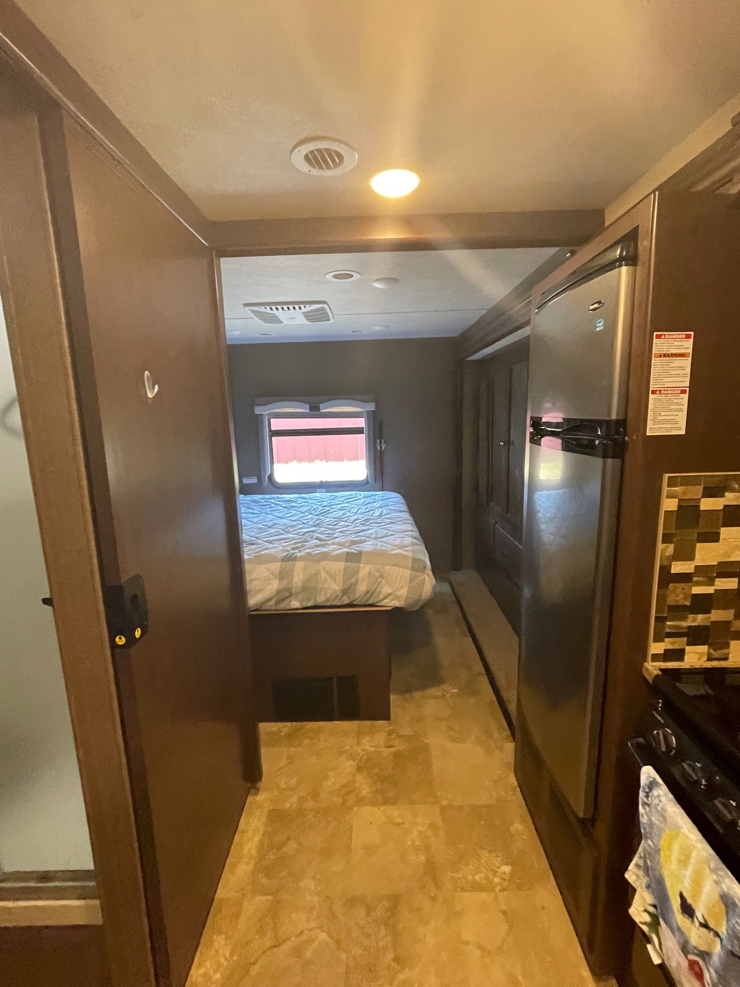 Experience an RV rental: Hallway view with a bedroom, compact kitchen with fridge, and a watchful cat behind a door.. Thor Windsport 2018