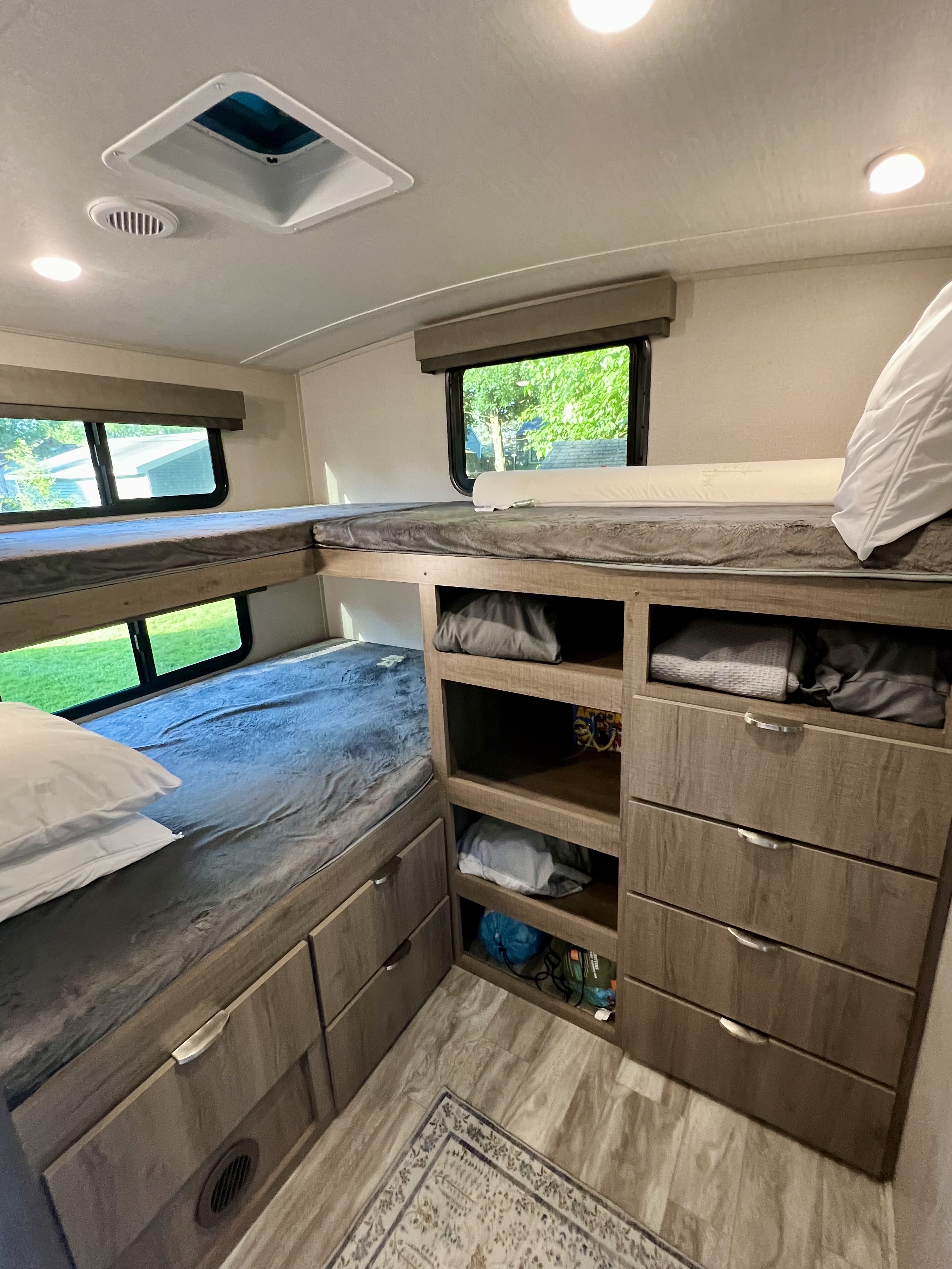 Cozy bunk beds and storage inside an RV rental, with natural light from windows and ample space for belongings.. Grand Design Imagine 2020