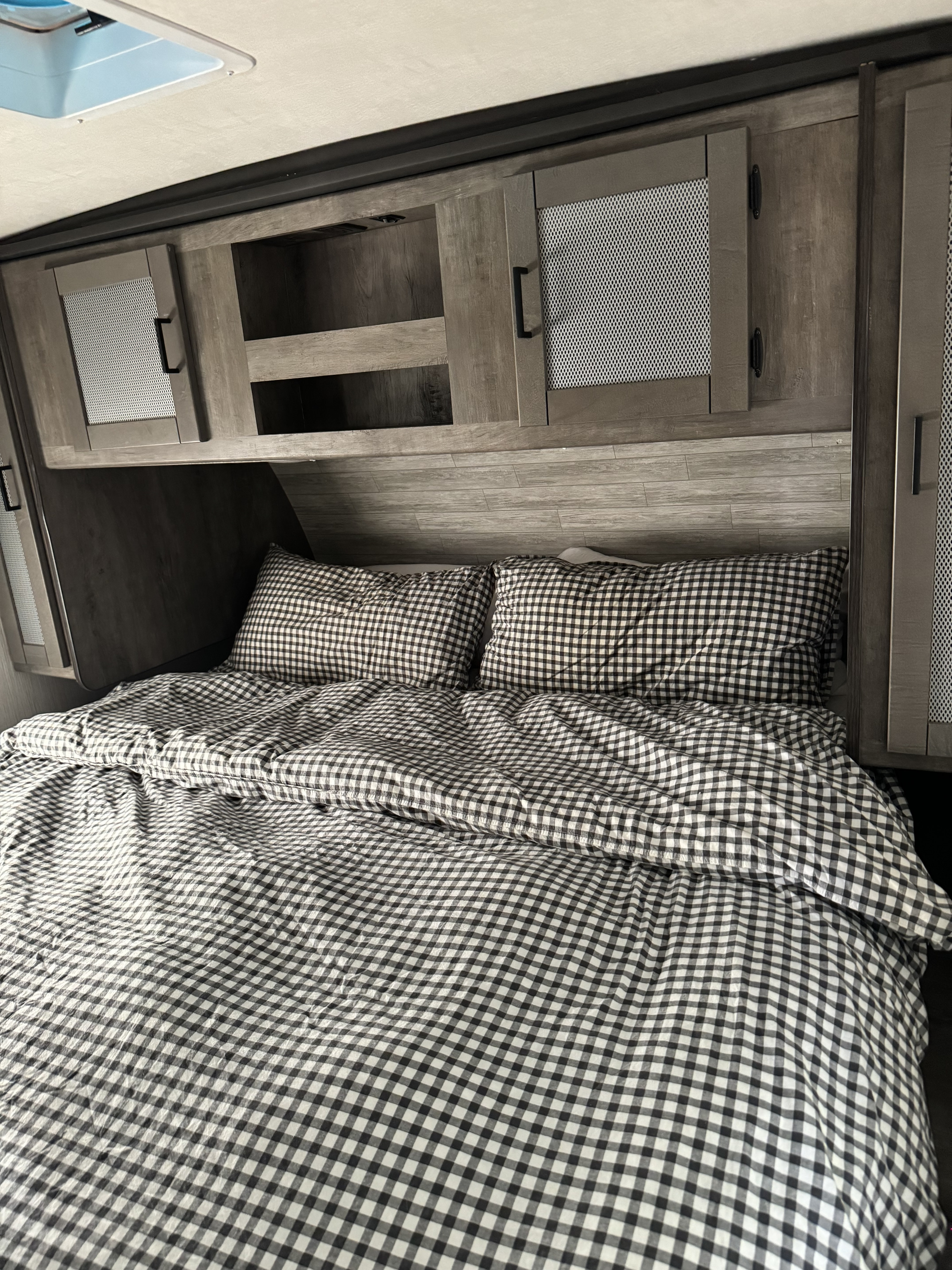 RV rental bed with cozy gingham bedding & overhead storage cabinets. Ideal for a comfortable sleep on your adventures.. Heartland RVs Wilderness 2021