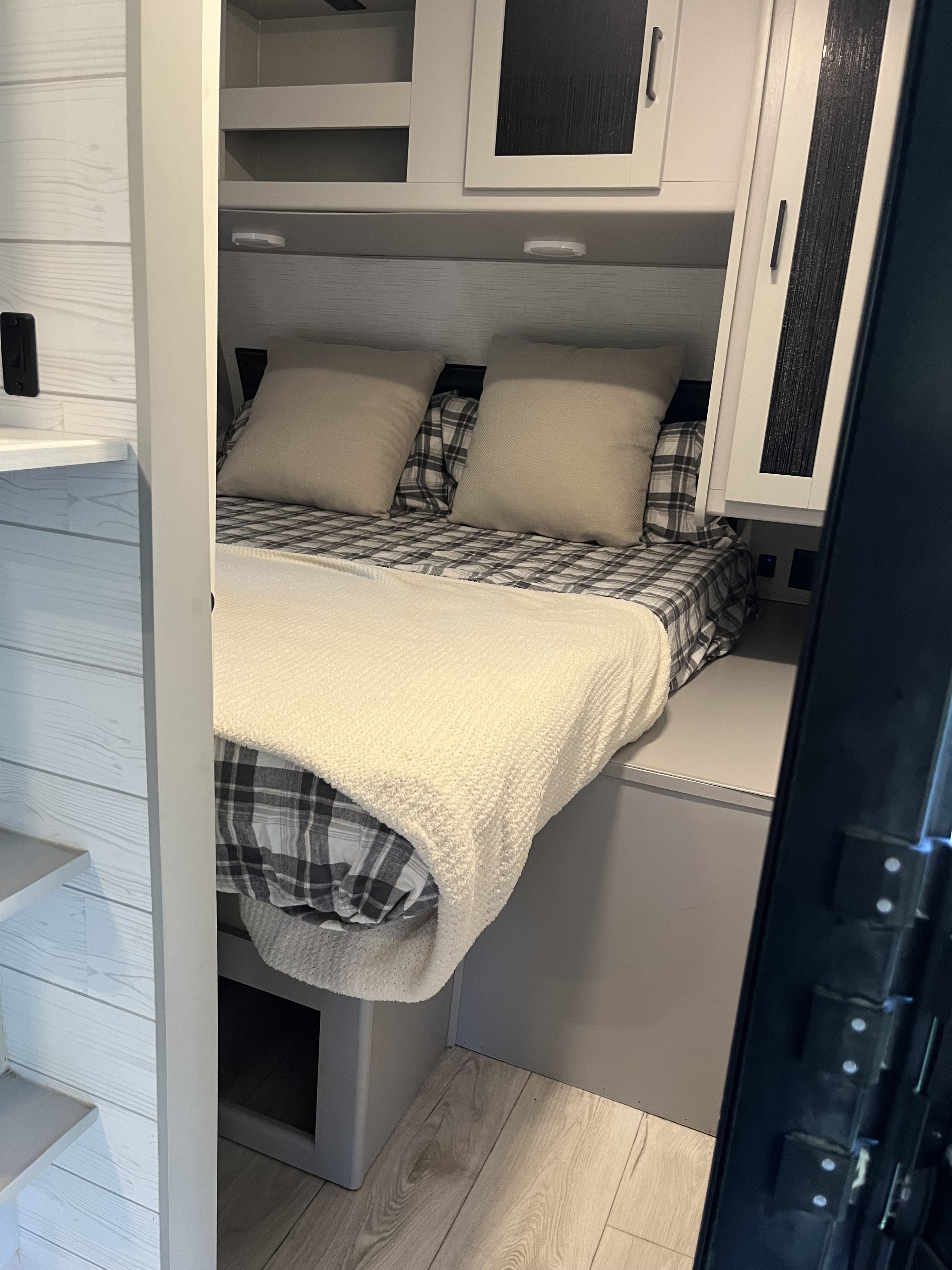 Cozy RV rental bedroom with plaid bedding, soft pillows, and smart overhead storage for travelers.. Heartland RVs North Trail 2022