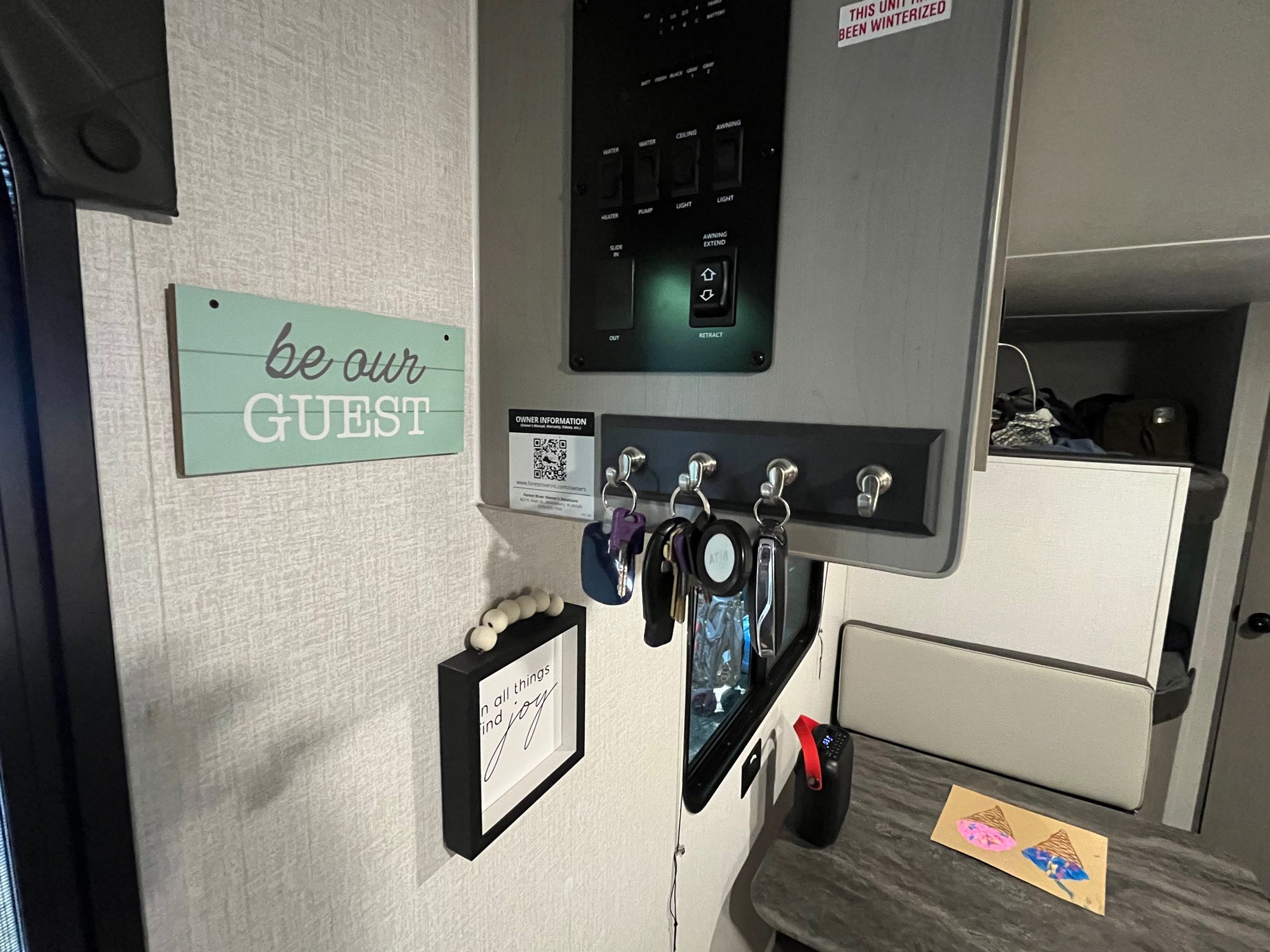Comfortable RV rental interior: A central control panel, key rack, "Be Our Guest" sign, and cozy bunk area are visible.. Coachmen Clipper 2024