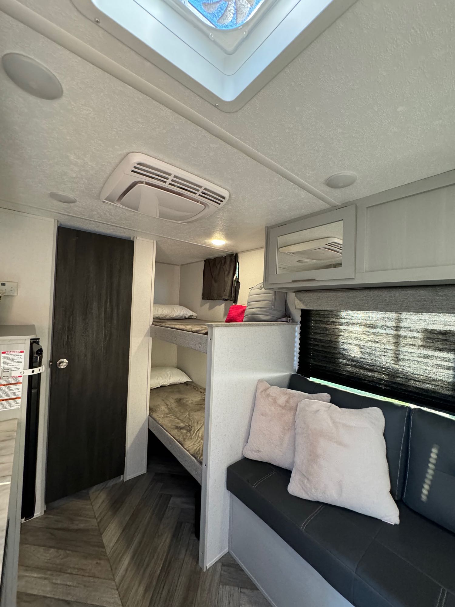 Cozy RV rental interior with bunk beds, dark sofa, and overhead storage, offering a compact living space.. Forest River Wildwood FSX 2023