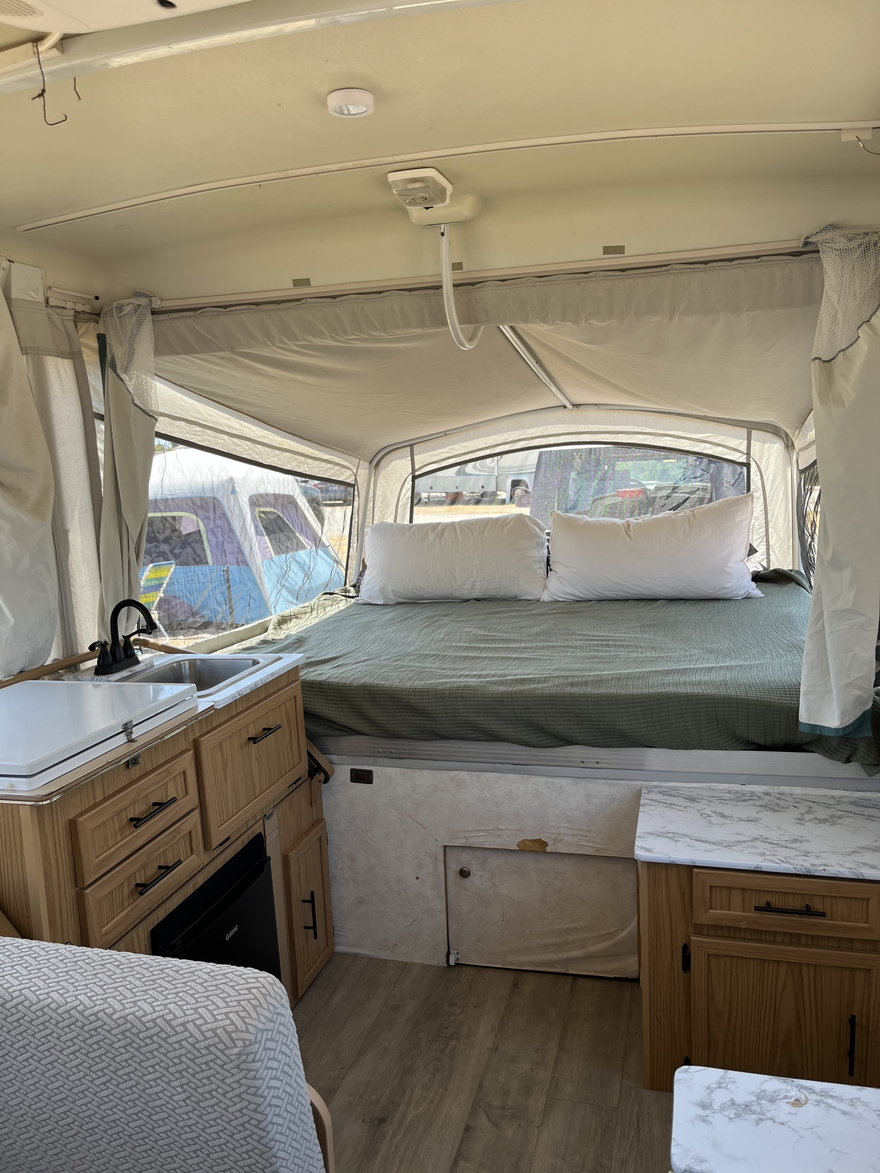 Inside this RV rental pop-up camper: a comfy bed, functional kitchen with a sink, and organized storage. Ideal for adventurers.. Coleman Destiny Cheyenne 1998