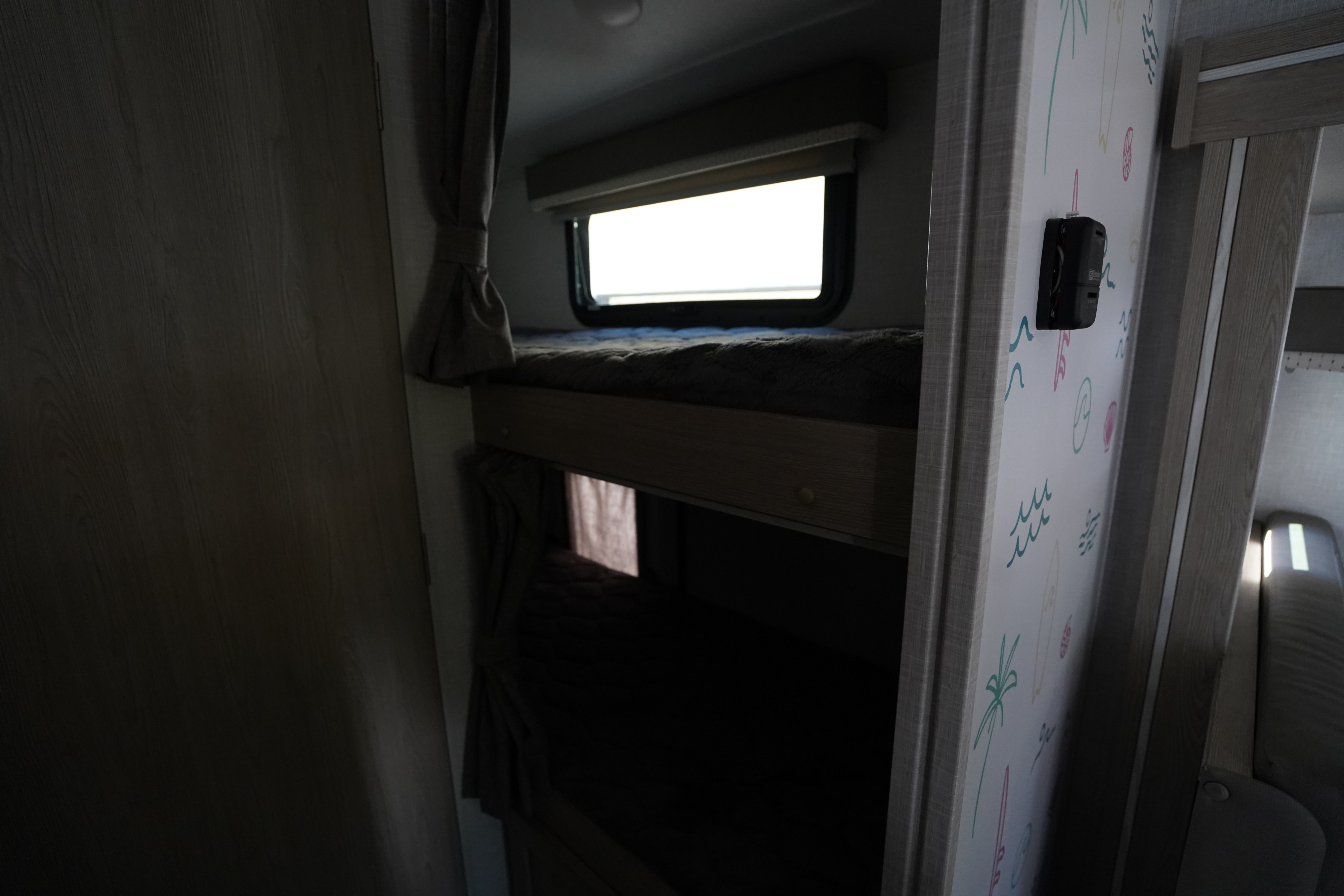 Inside an RV rental: bright window by the top bunk, with lower bunk and playful wall decals.. Forest River Rockwood 2021
