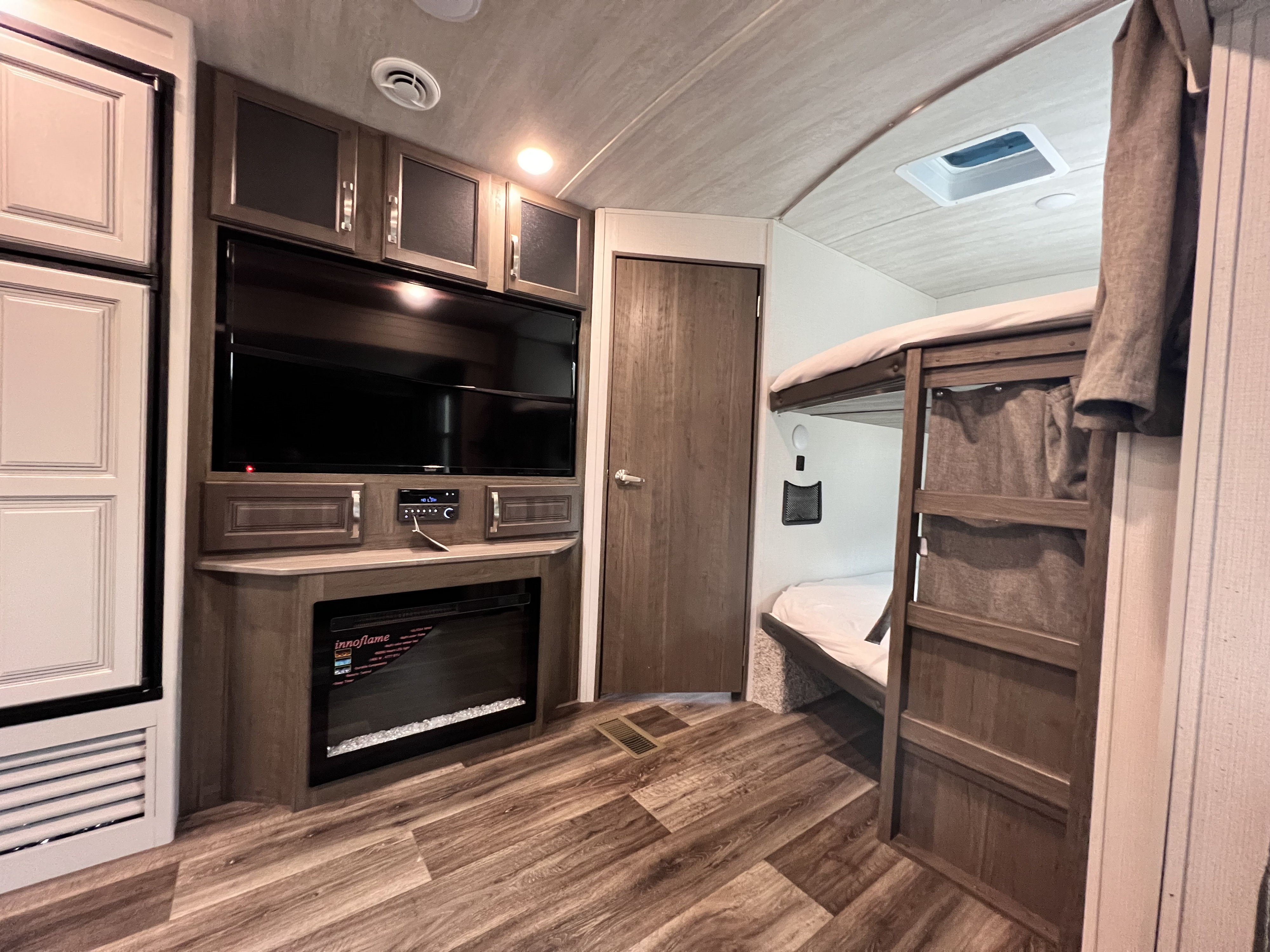 Spacious RV rental interior with bunk beds, an entertainment system, fireplace, and kitchen amenities.. Keystone RV Cougar 2022