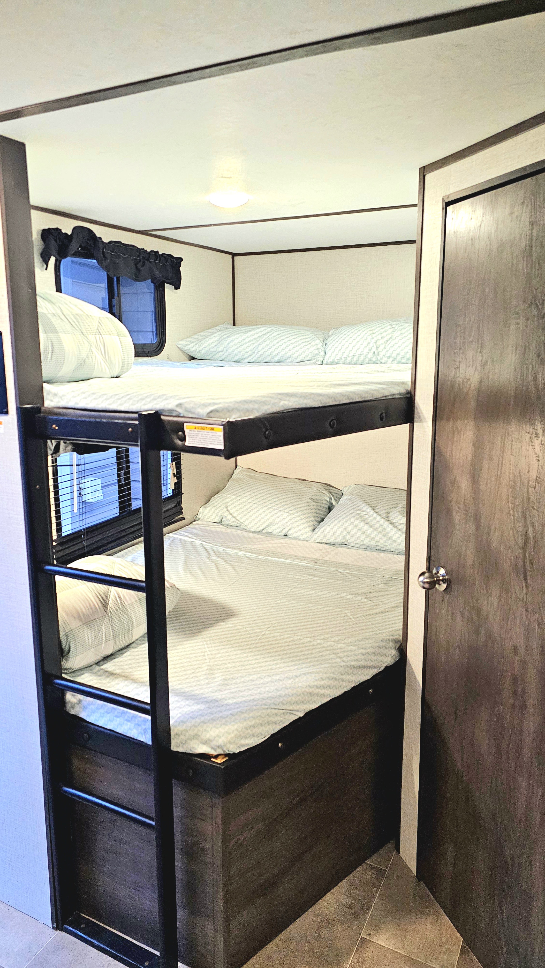 RV rental: View of two stacked bunk beds with light blue bedding, a ladder, and windows, offering cozy sleeping.. Dutchmen Coleman Light 2021