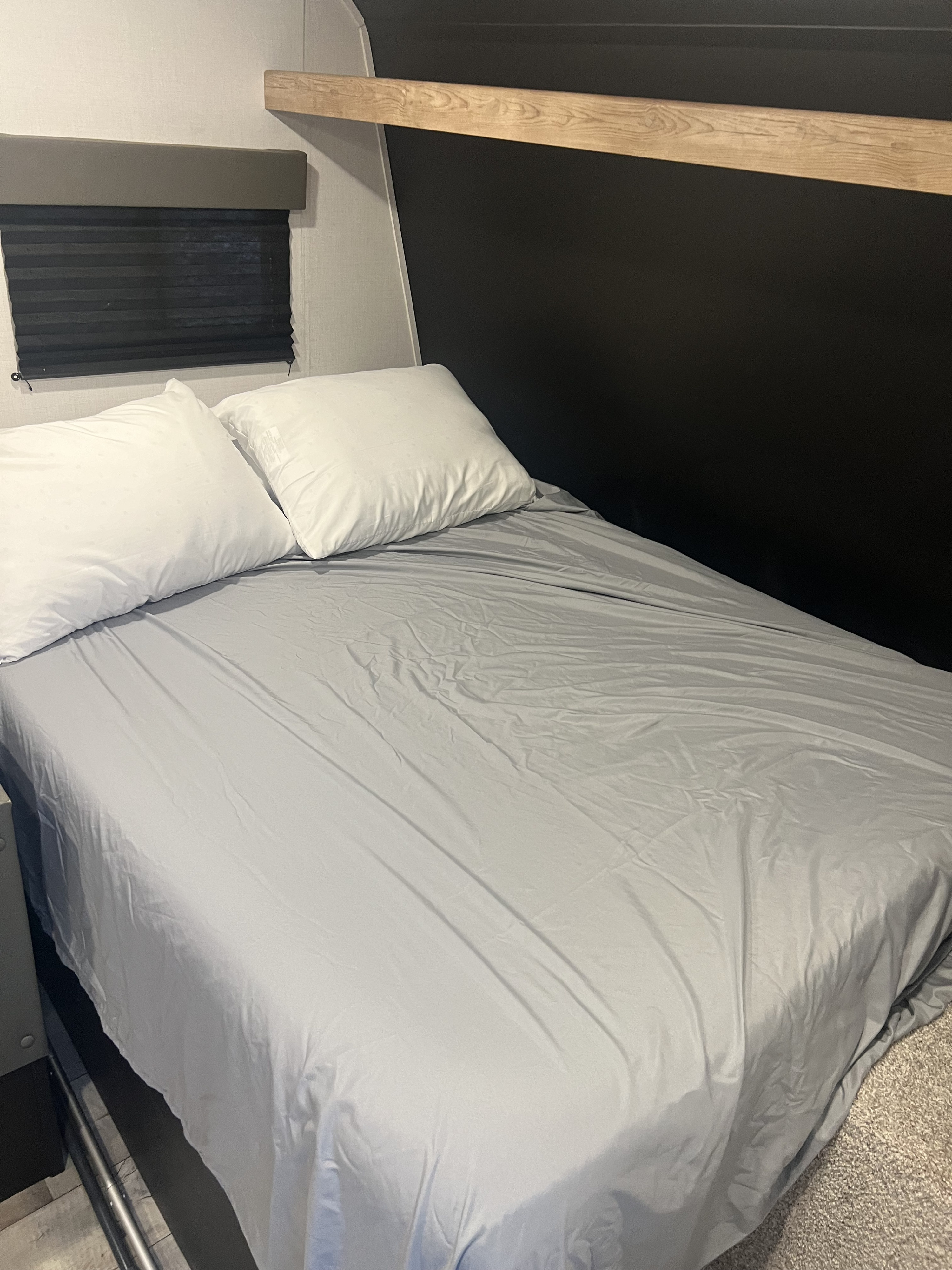 RV rental bedroom: A neatly made bed with white pillows and light gray sheets, a window blind, and wood trim.. Keystone RV Springdale 2023