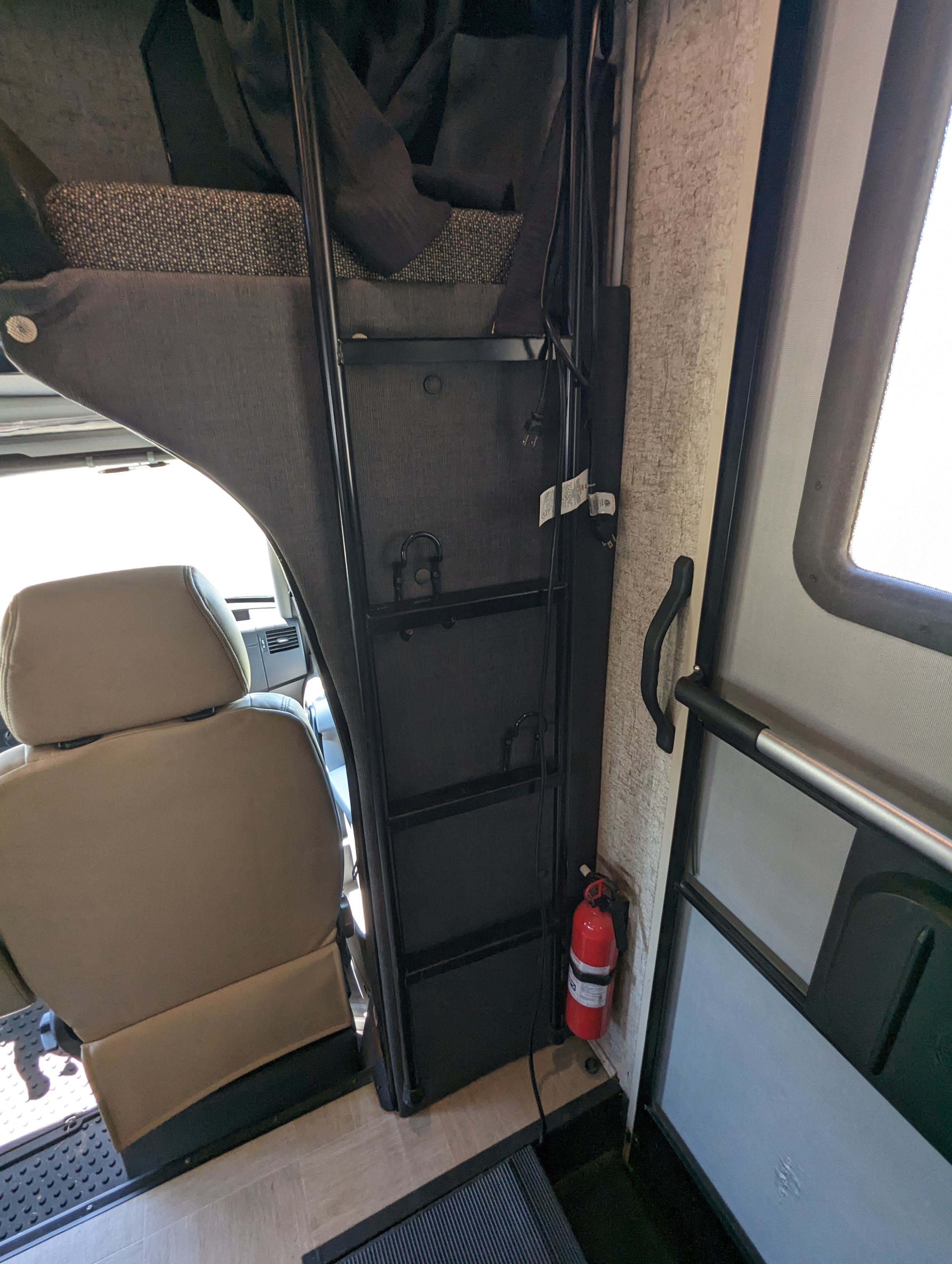 RV rental interior featuring a bunk bed with ladder, driver's seat, a fire extinguisher, and the entry door.. Forest River Coachmen Prism 2018