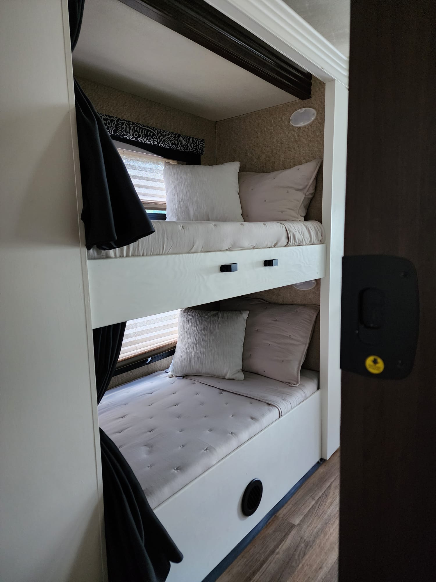 Cozy bunk beds in an RV rental, featuring soft bedding, window blinds, and personal lighting for comfortable sleep.. Thor A.C.E. 2018