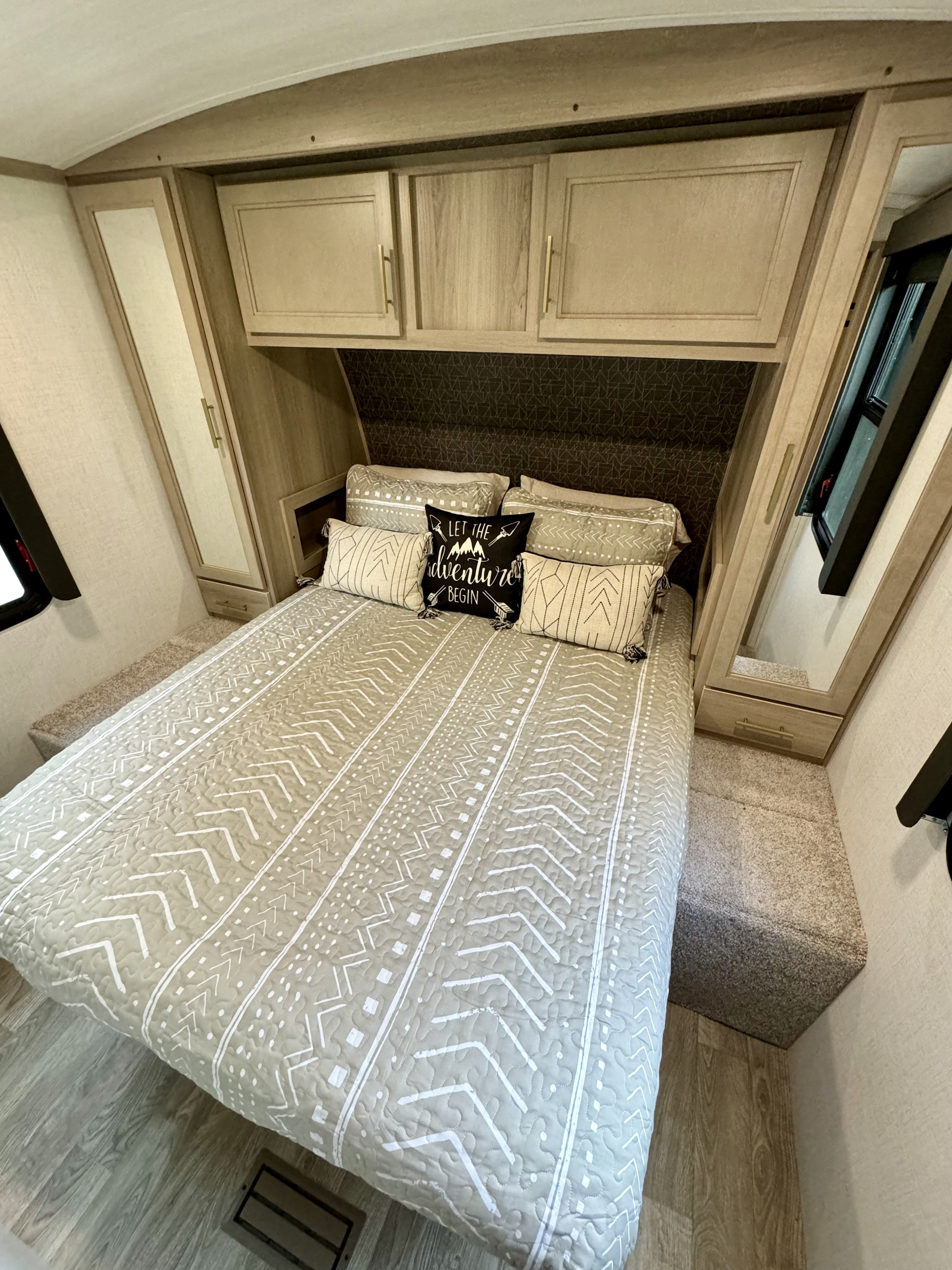 Cozy RV rental bedroom with patterned bedding & overhead storage. Ready for your next adventure!. Keystone RV 340BH 2024