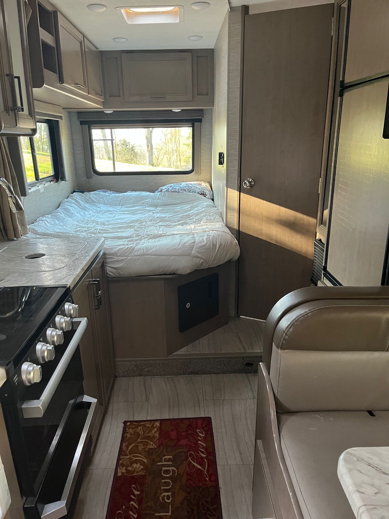 This RV rental interior shows a cozy bedroom, a functional kitchen with stove and sink, and a comfortable dinette area, perfect for travel.. Thor Motor Coach Coleman 2021
