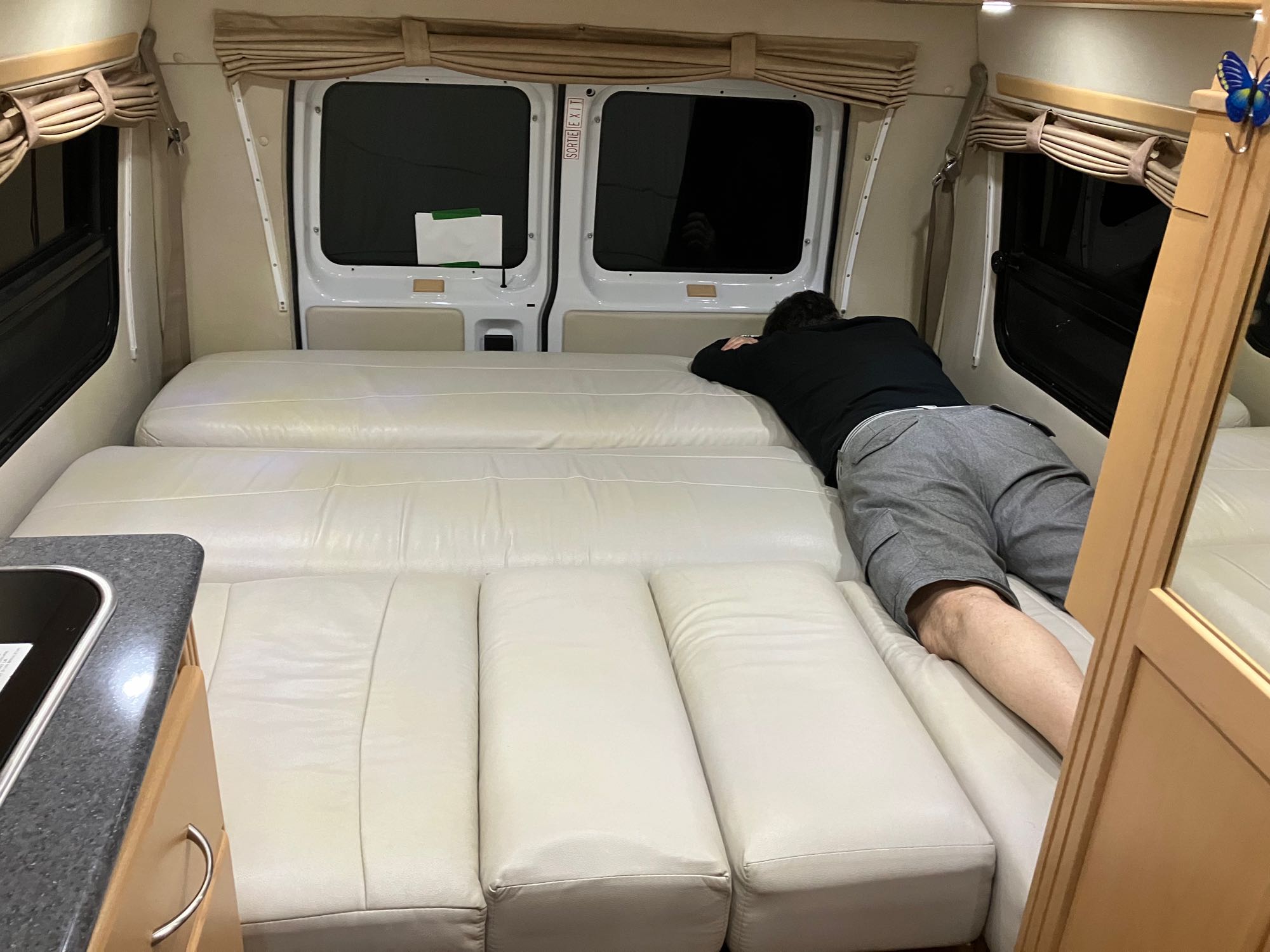 Inside an RV rental, a person relaxes on comfortable cushions in the spacious, well-appointed travel living area.. Pleasure-Way Pleasure-Way Class B 2011