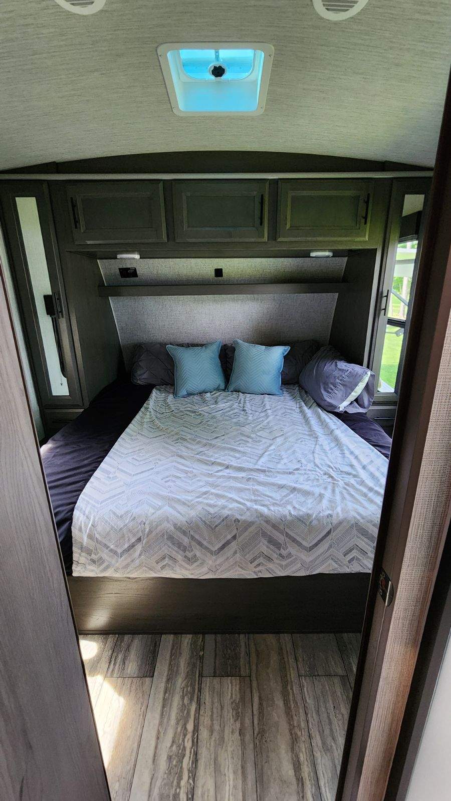 Cozy RV rental bedroom features a queen bed with overhead cabinets, side storage, and a ceiling vent.. Heartland Fuel 305 2020