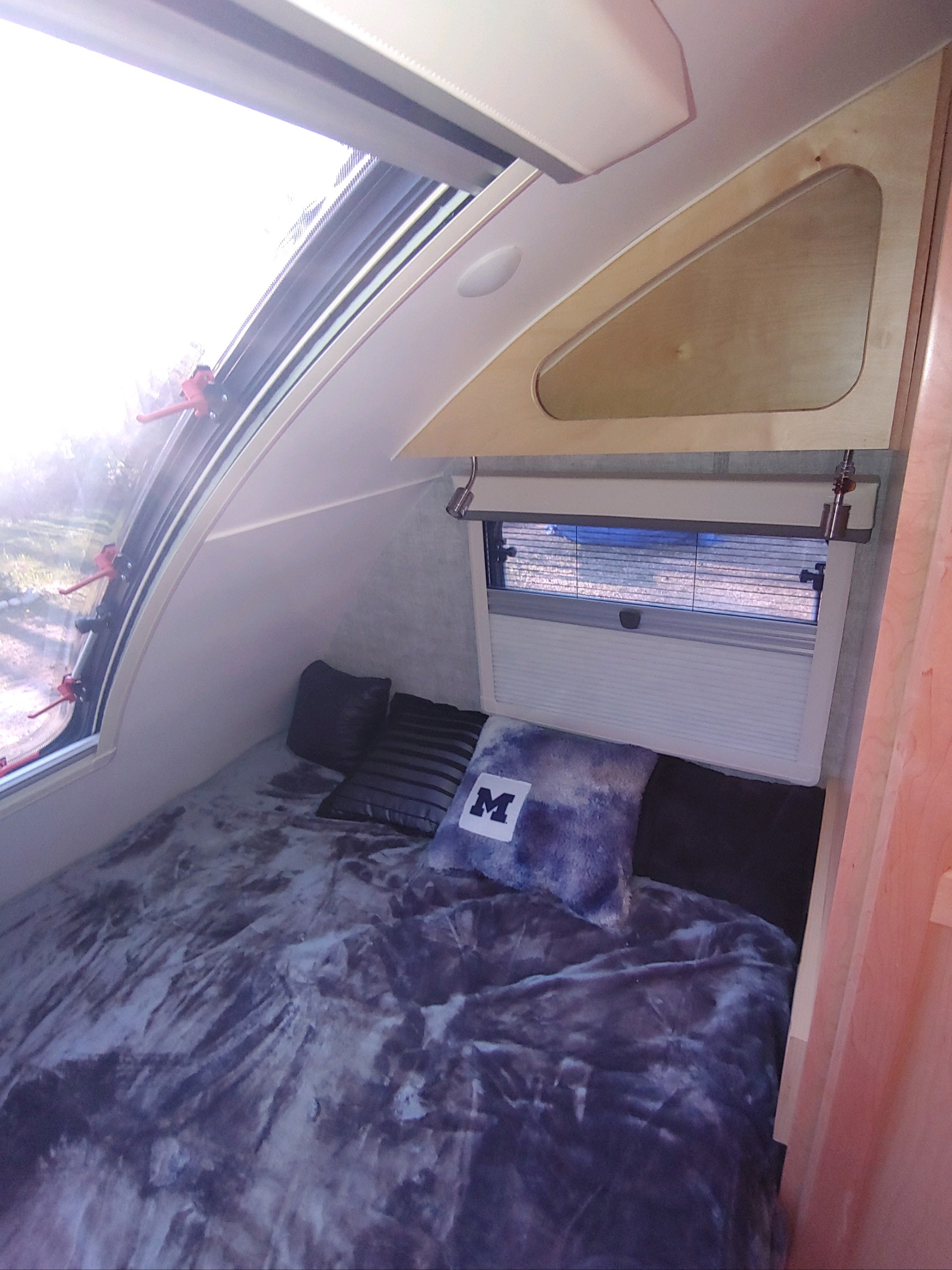 Inside a cozy RV rental: A comfortable bed with themed pillow, large side window, and rear window with blinds.. Little Guy Little Guy Trailer 2022
