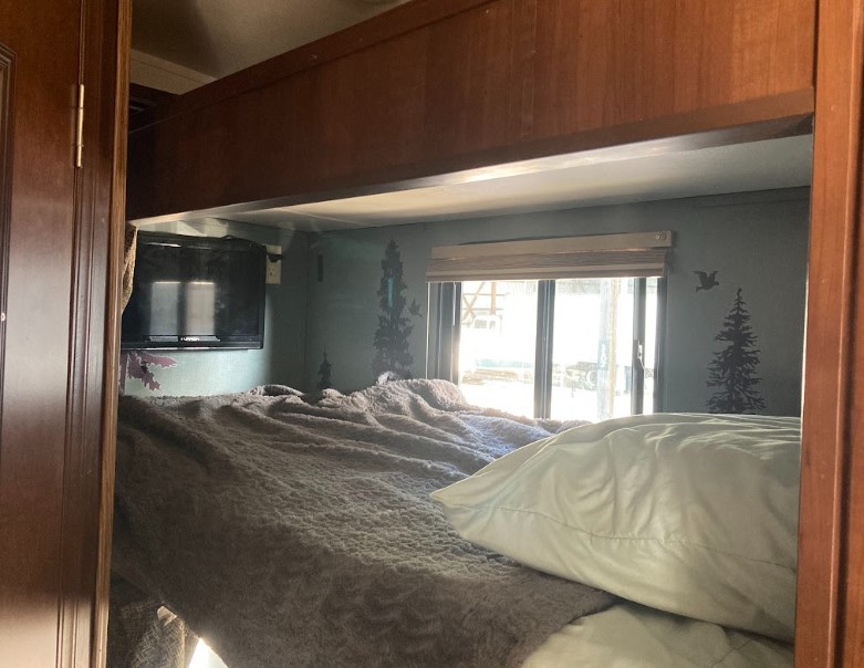Cozy RV rental bedroom with comfy bed, wall TV, and window showing nature art.. Georgetown GT3 2016