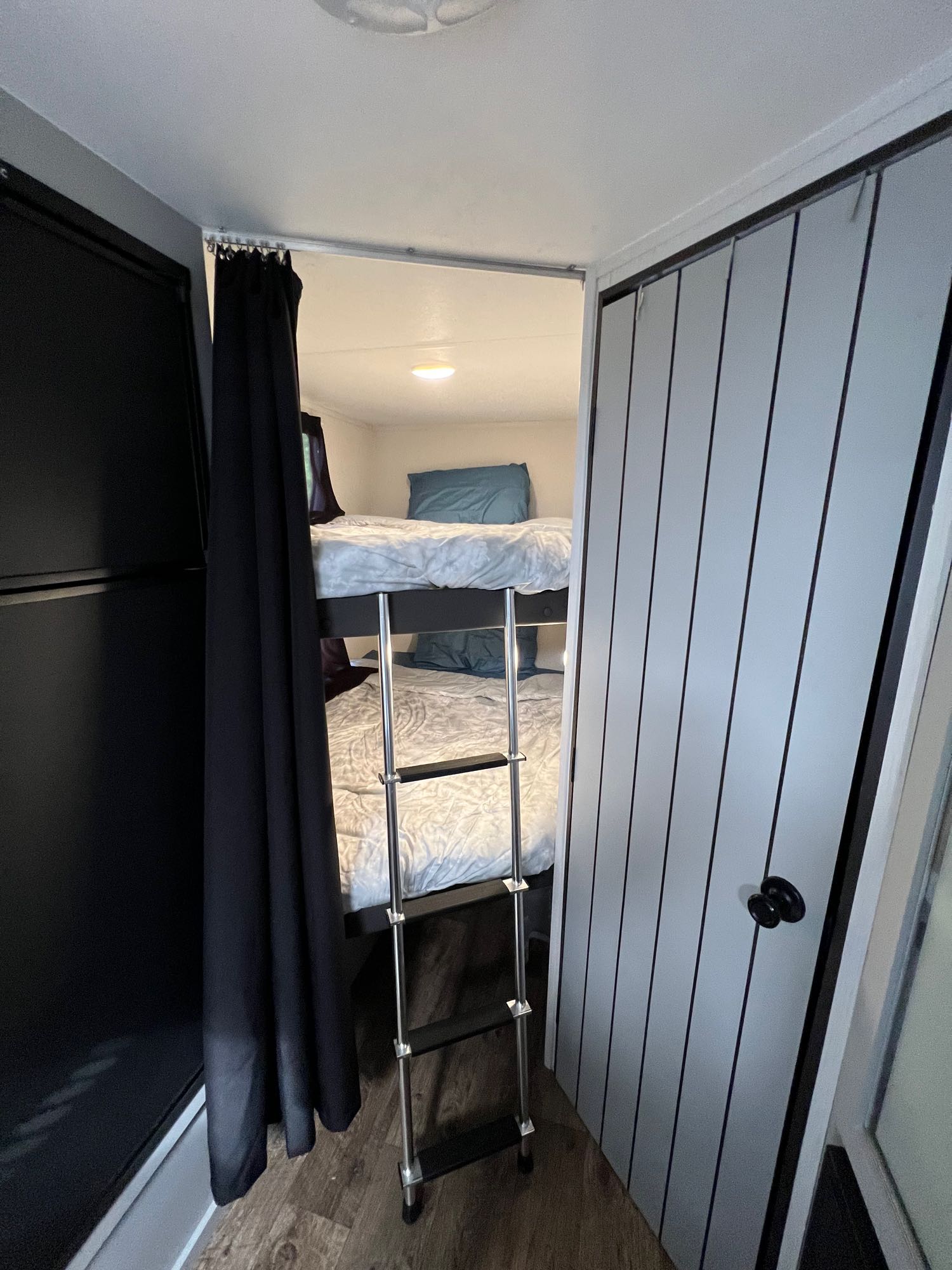 Cozy RV rental bunk beds with ladder and privacy curtain. Ideal compact sleeping for your travel adventures.. Forest River Rainier 24DBR 2022