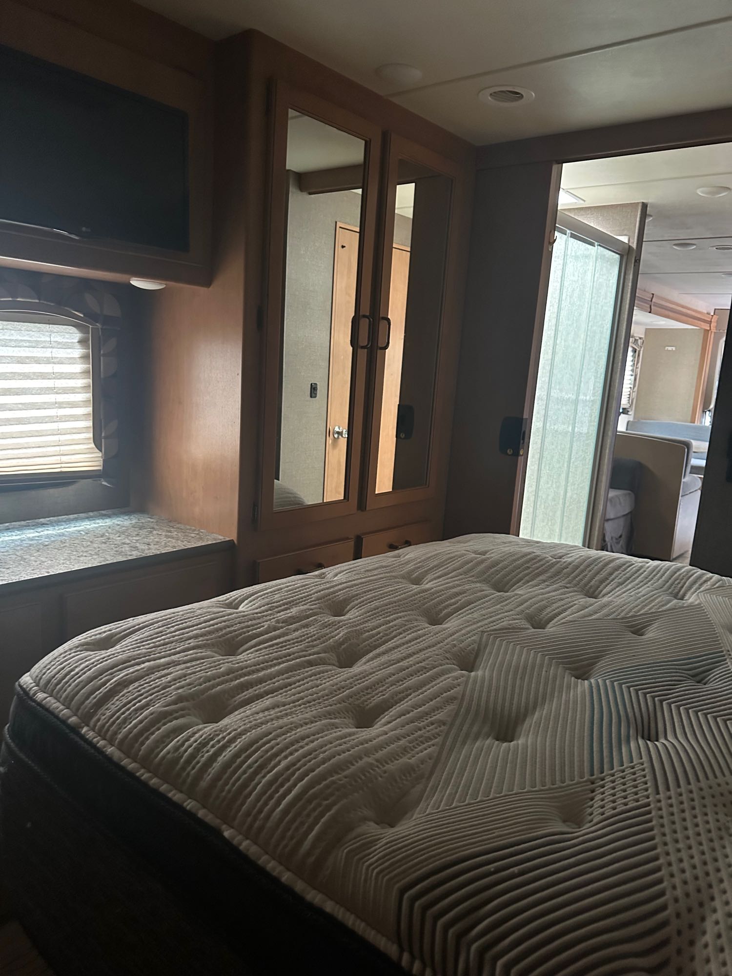 RV rental bedroom featuring a comfortable mattress, built-in storage, TV, and a sliding door. Perfect compact interior for travel.. Thor Hurricane 2017