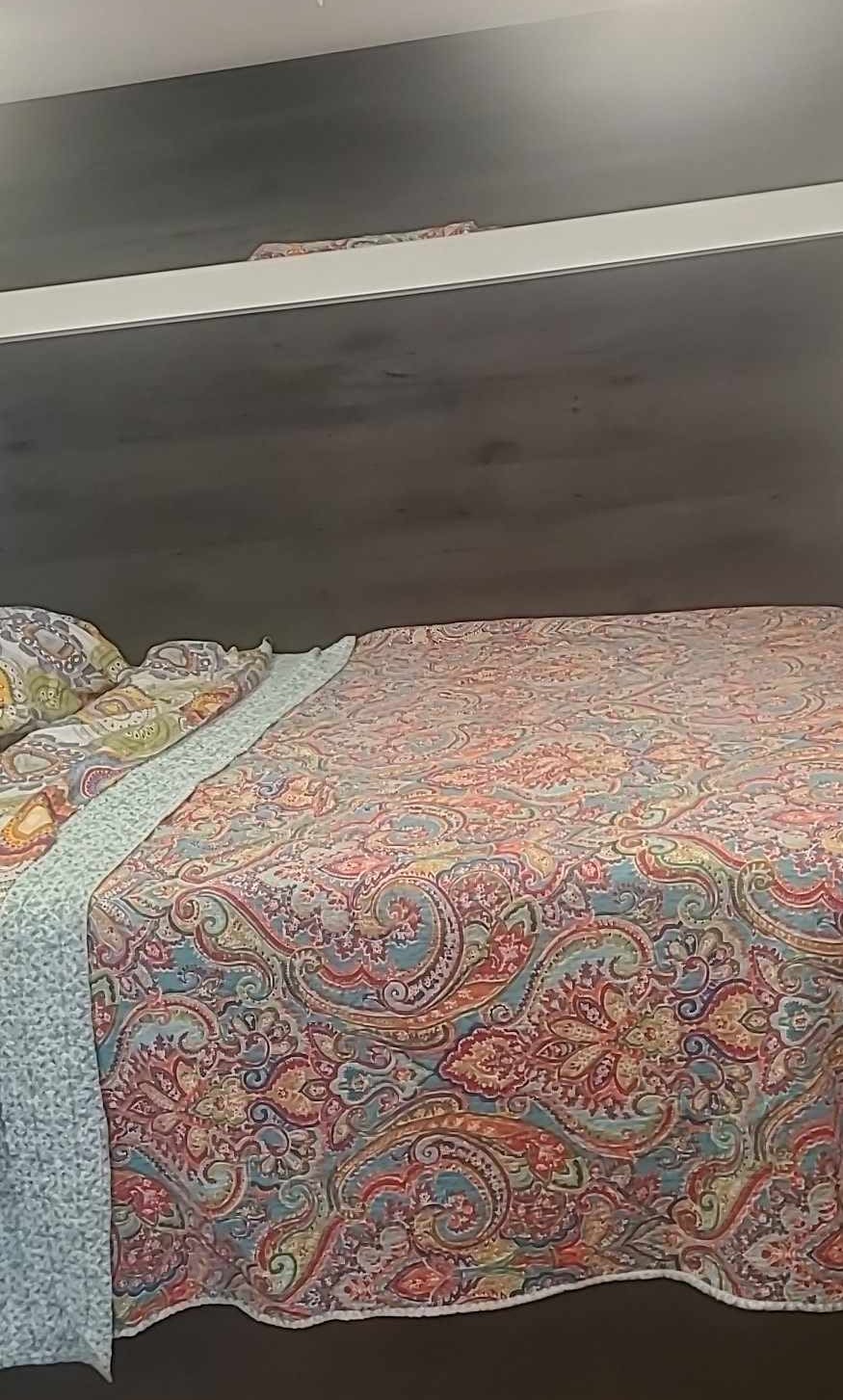 Inside an **RV rental**: a compact bed with colorful paisley bedding and pillows, designed for comfort on the road.. Keystone RV Hideout 2023