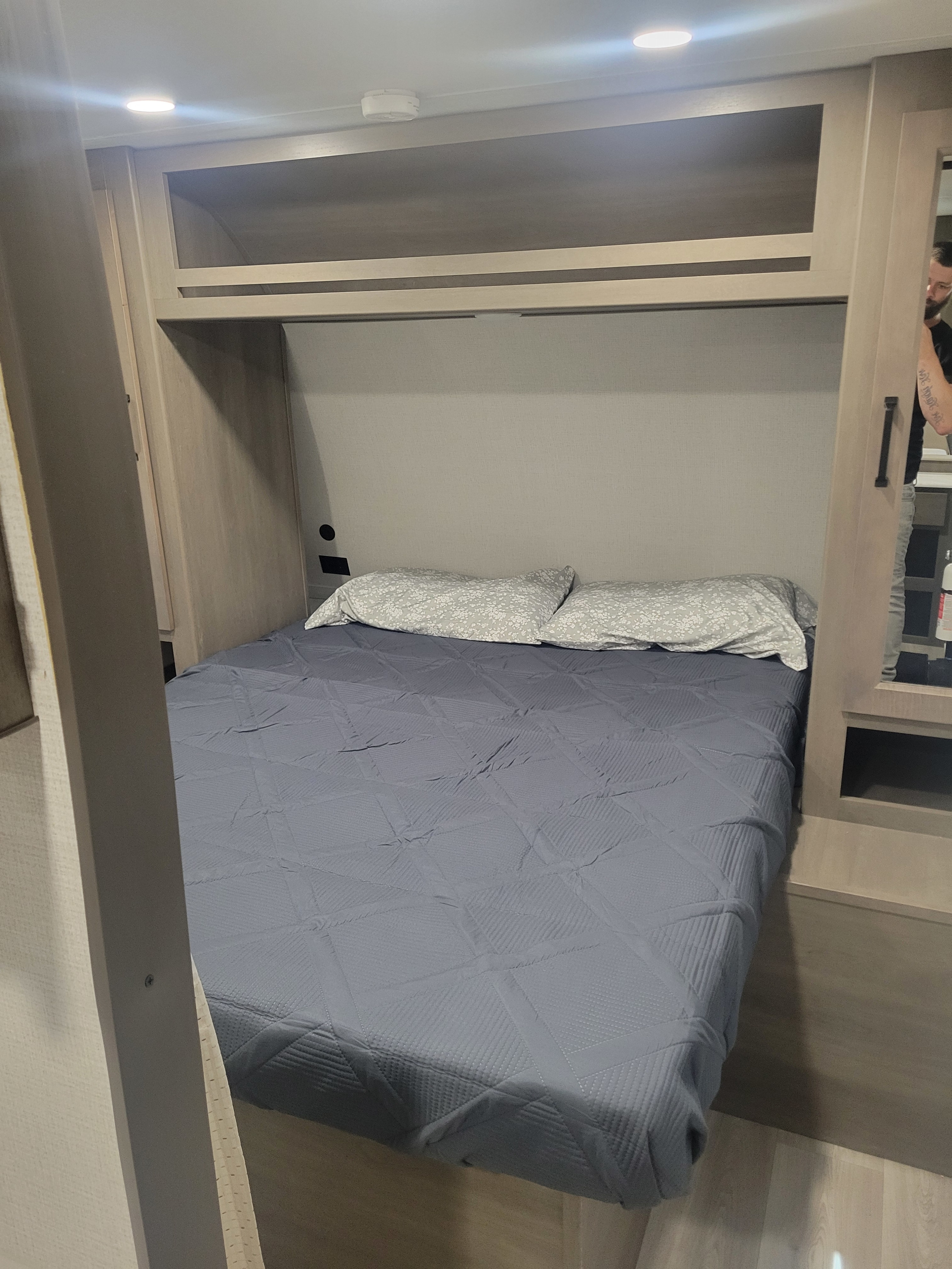 Cozy RV rental bedroom with comfortable bed, overhead storage, and modern lighting for a relaxing stay.. Transcend 247bhx 2024