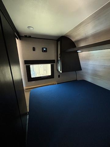 Cozy RV rental bedroom features a dark blue bed, window, wall controls, and overhead storage.. Jayco Jay Flight 2022