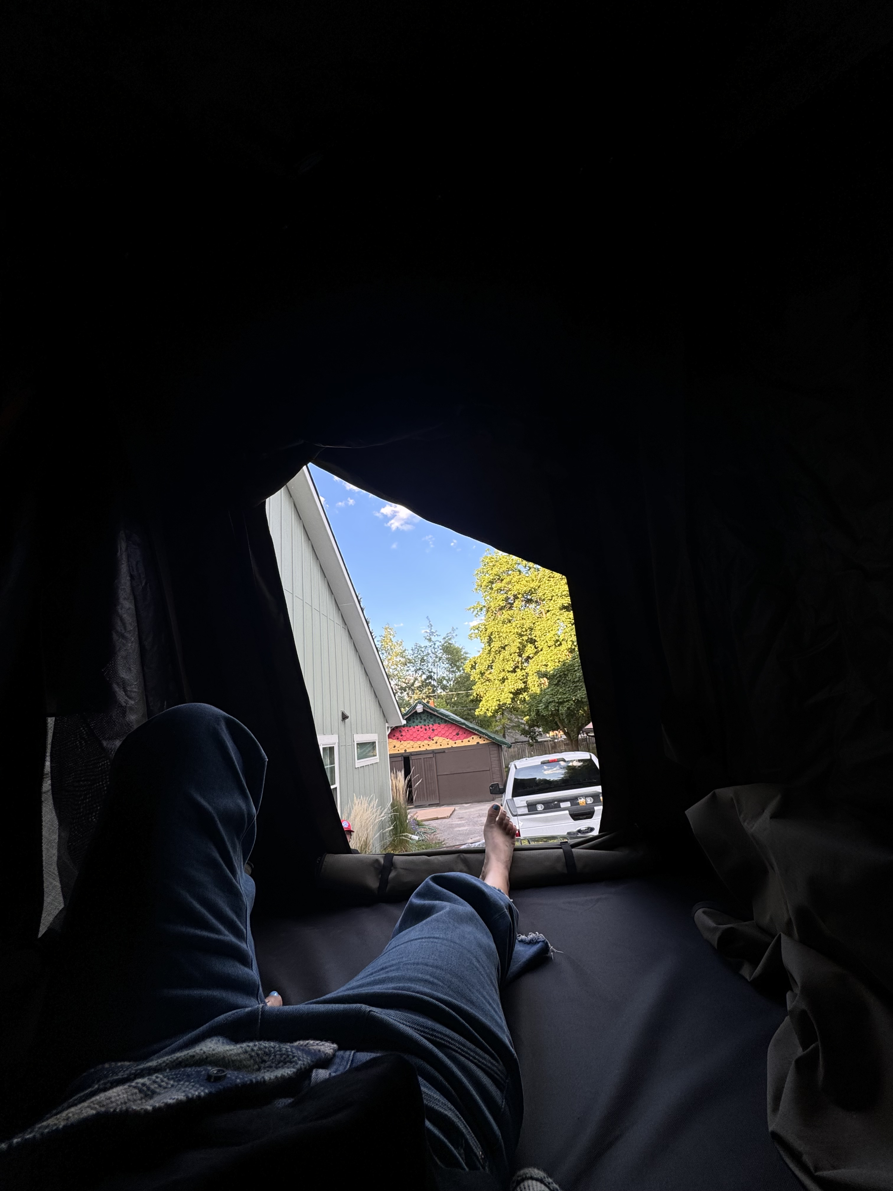 Cozy view from an RV rental's rooftop tent, relaxing with legs stretched out overlooking a neighborhood.. Ford Ford F150 2013