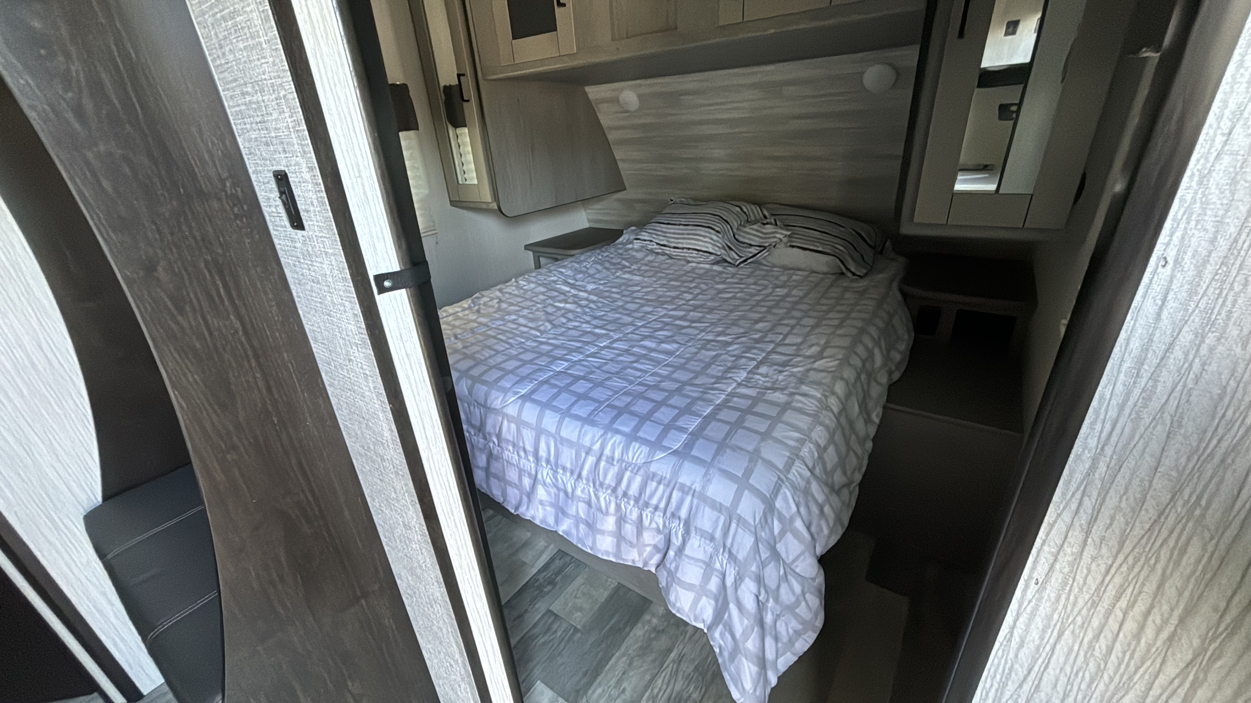 Cozy RV rental bedroom with a comfy bed, overhead cabinets, and nightstands. Ideal for road trip relaxation!. Heartland m 2020