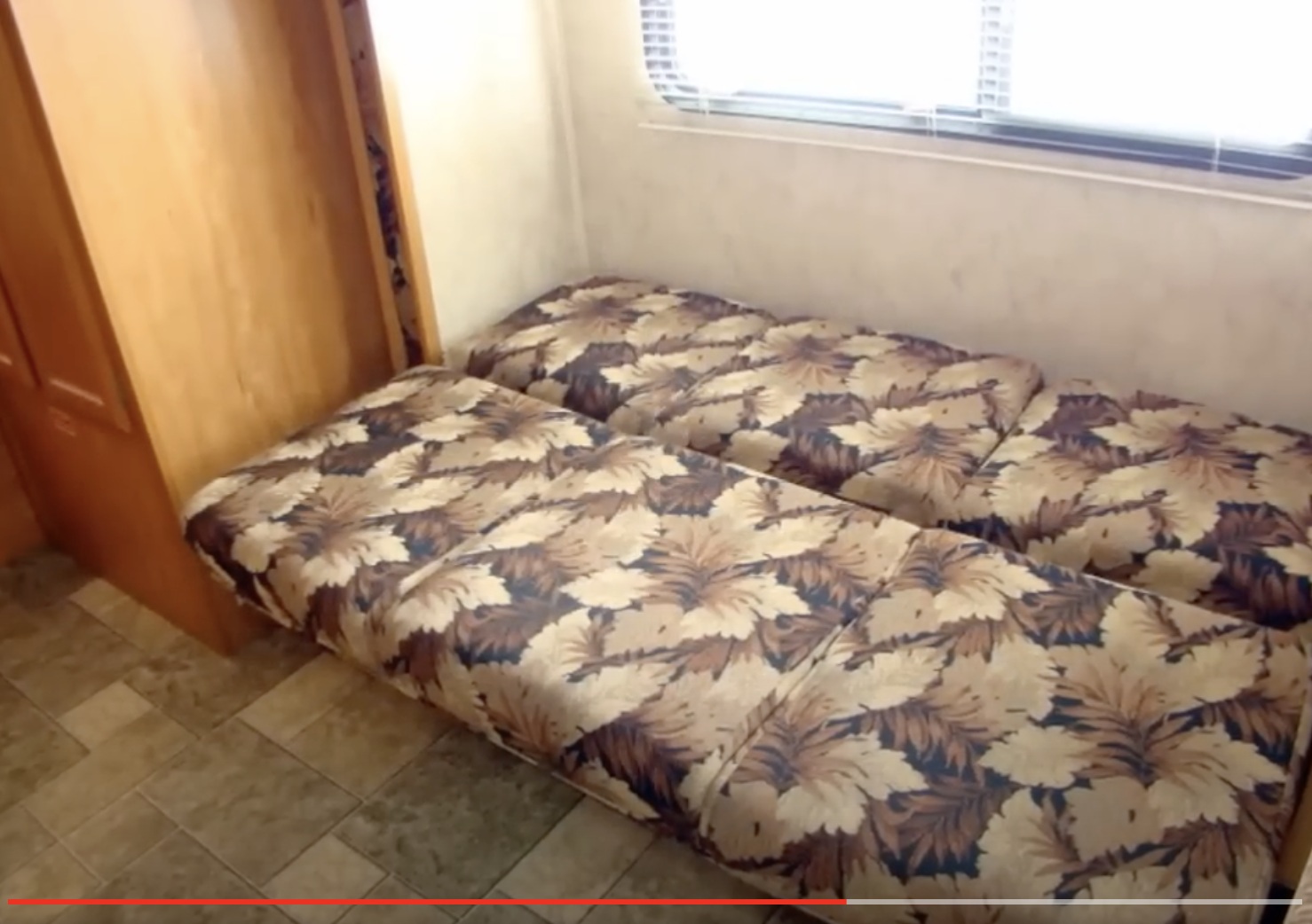 RV rental interior features a convertible sofa bed with leaf pattern, window, & wood cabinet in this travel trailer.. Dutchmen Kodiak Ultra Lite with 2 pop-up 2009