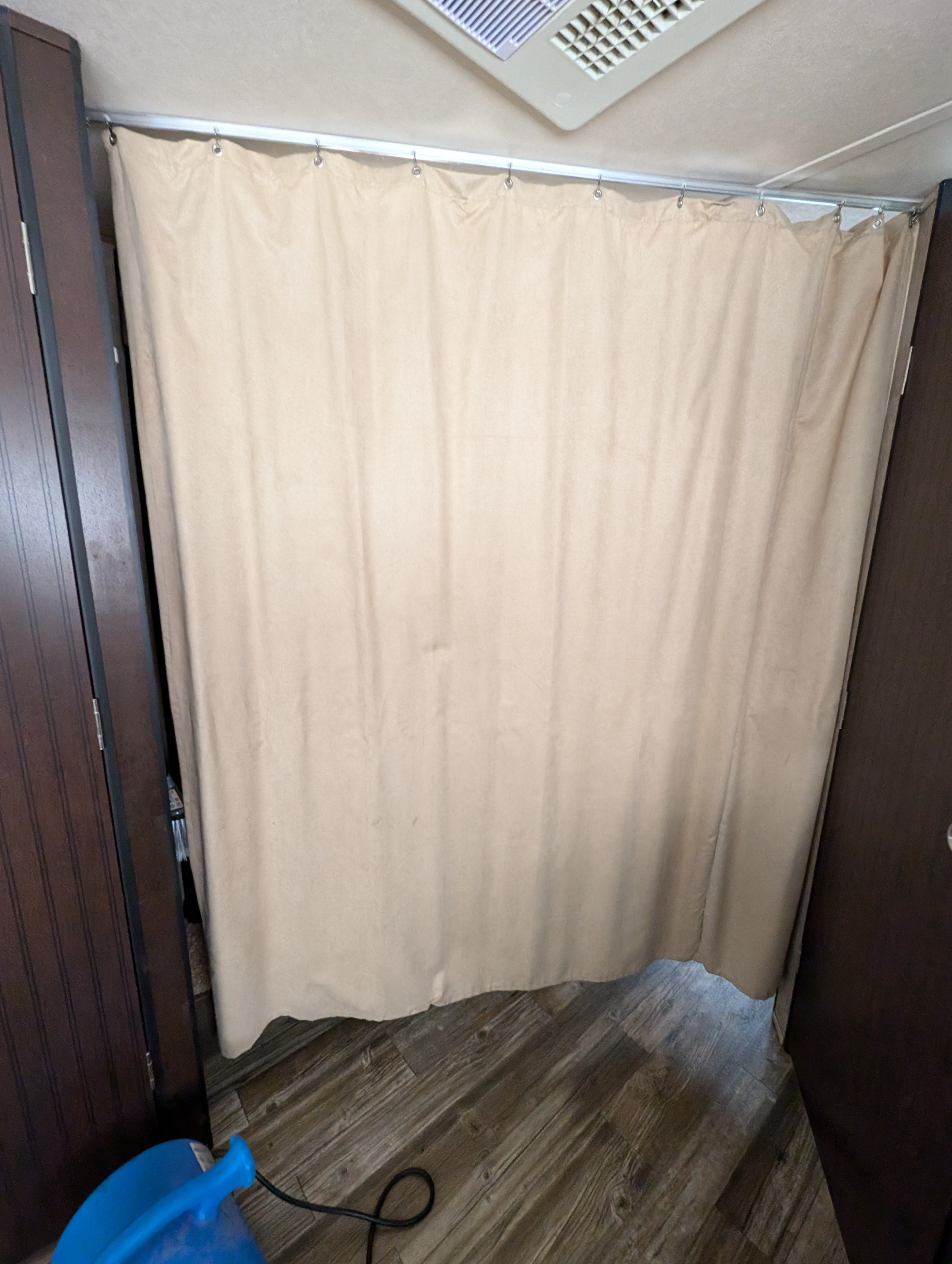 Beige privacy curtain dividing an RV rental interior, showing a rail, ceiling vent, and wood-look floor.. Forest River Cherokee Grey Wolf 2017