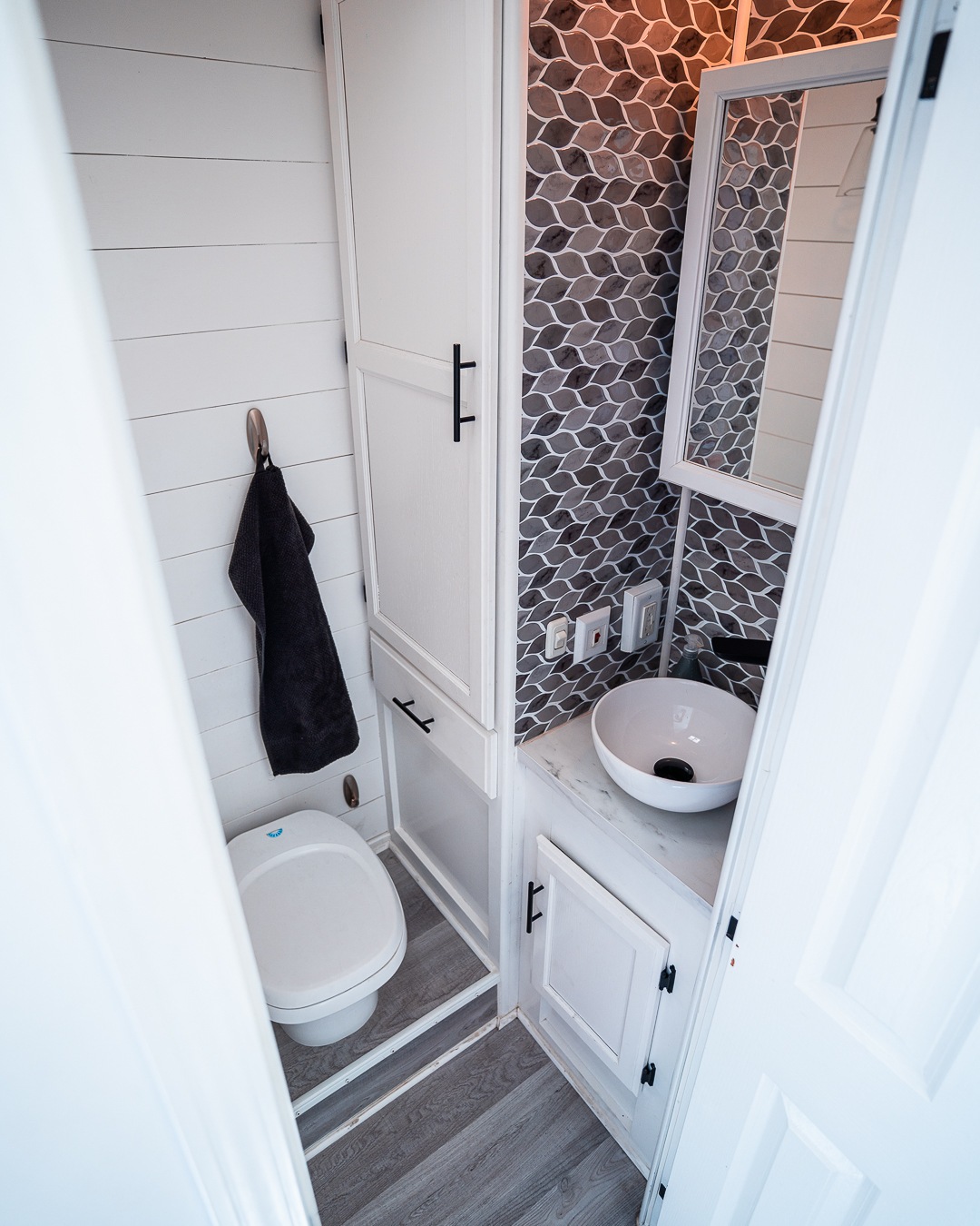 This compact RV rental bathroom showcases white shiplap walls, a modern toilet, vessel sink, mirror, and stylish tile backsplash.. Gulf Stream Conquest Classic 2004
