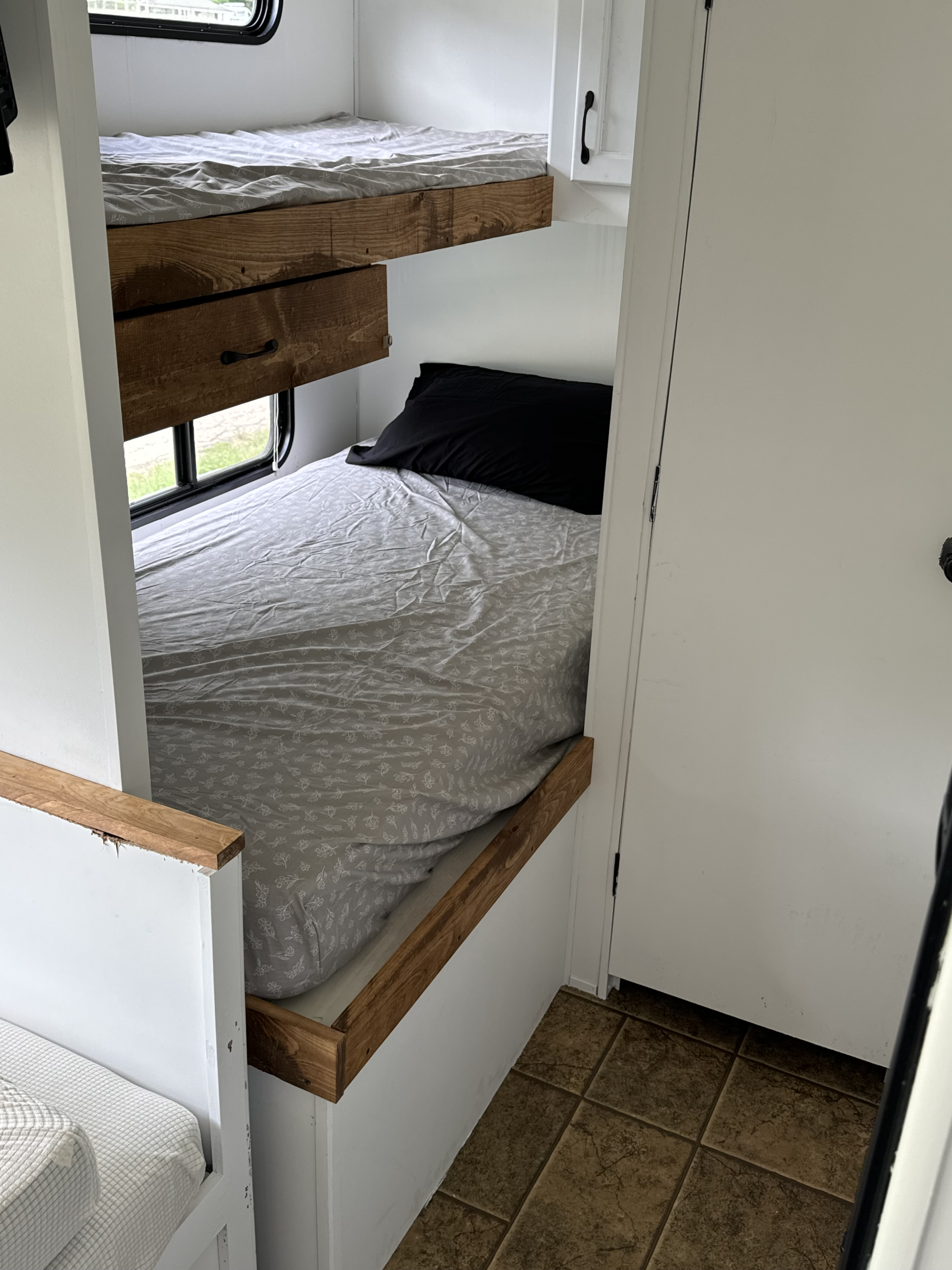 Cozy RV rental bunk beds with wood accents and a window. Perfect sleeping setup for family travel in your camper.. Forest River Cherokee Grey Wolf 2012