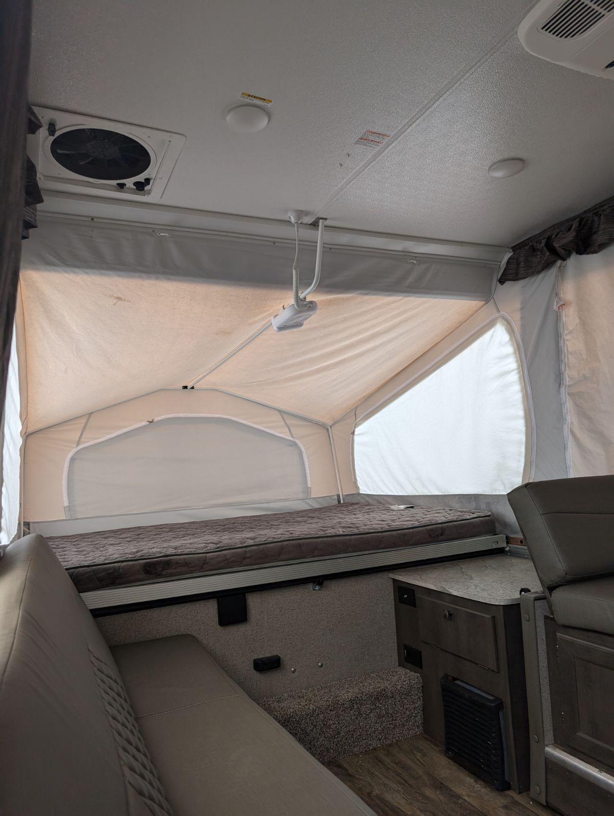 RV rental interior featuring a pop-up bed, seating, ceiling fan, and mini projector. Perfect for camper adventures.. Rockwood 2318g 2019