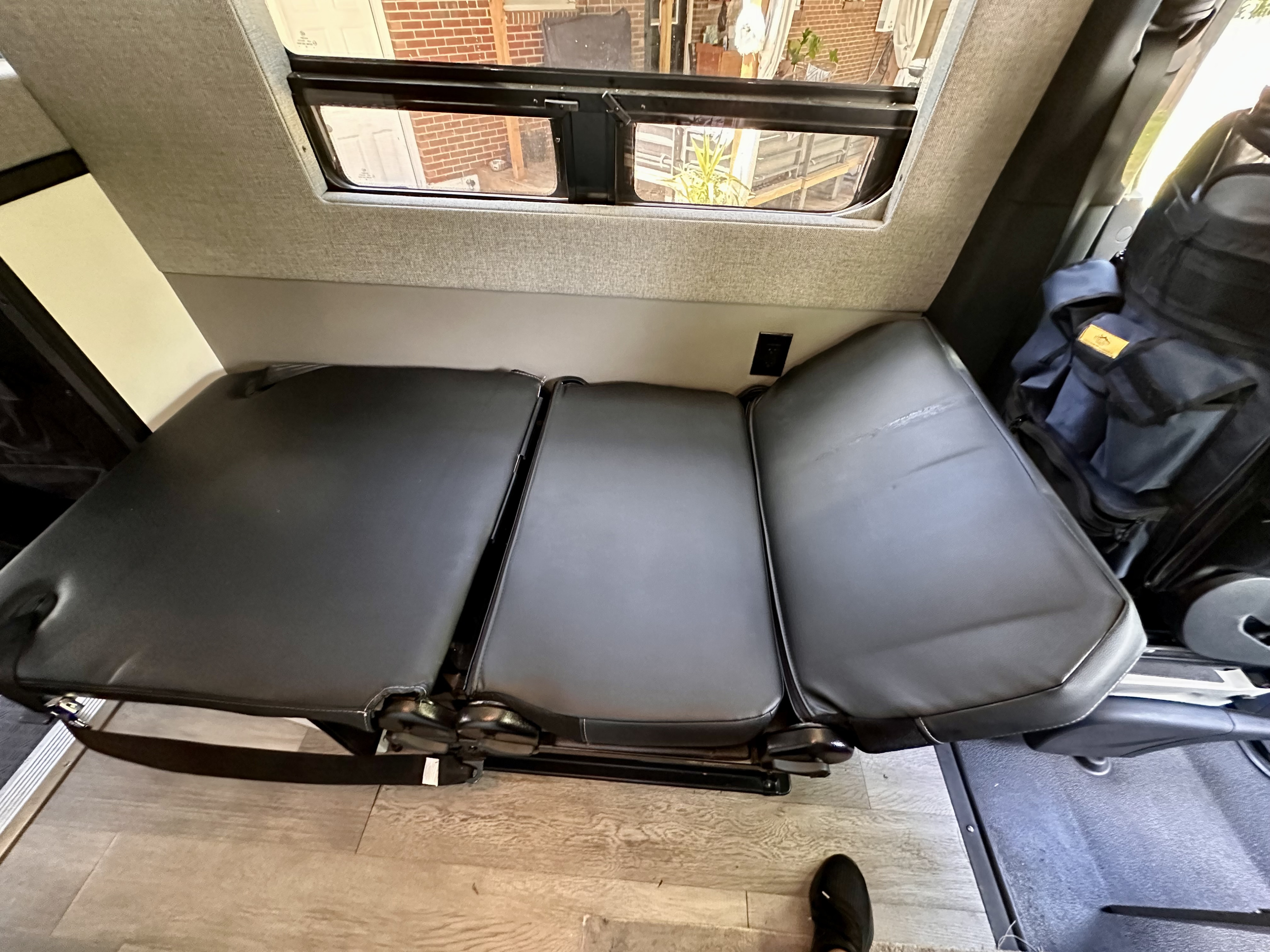 RV rental interior featuring a versatile three-section convertible bench seat with window view and power outlet.. Mercedes-Benz MB140 2022