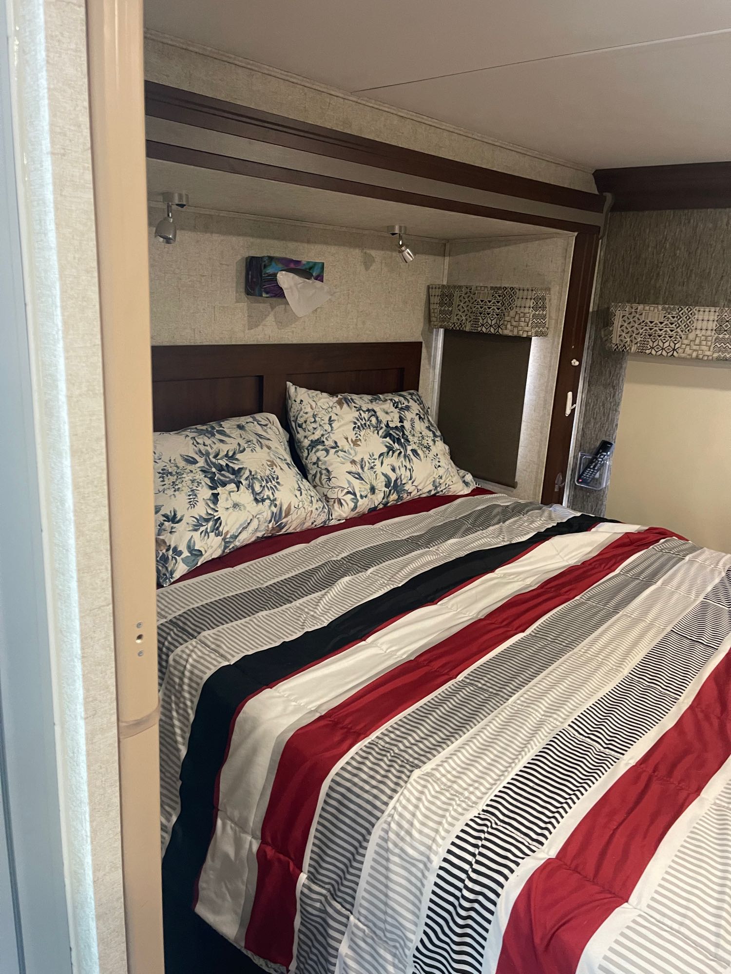 **RV rental bedroom:** Cozy, compact accommodations with striped bedding, floral pillows, reading lights & tissue box.. Forest River Sunseeker 2018