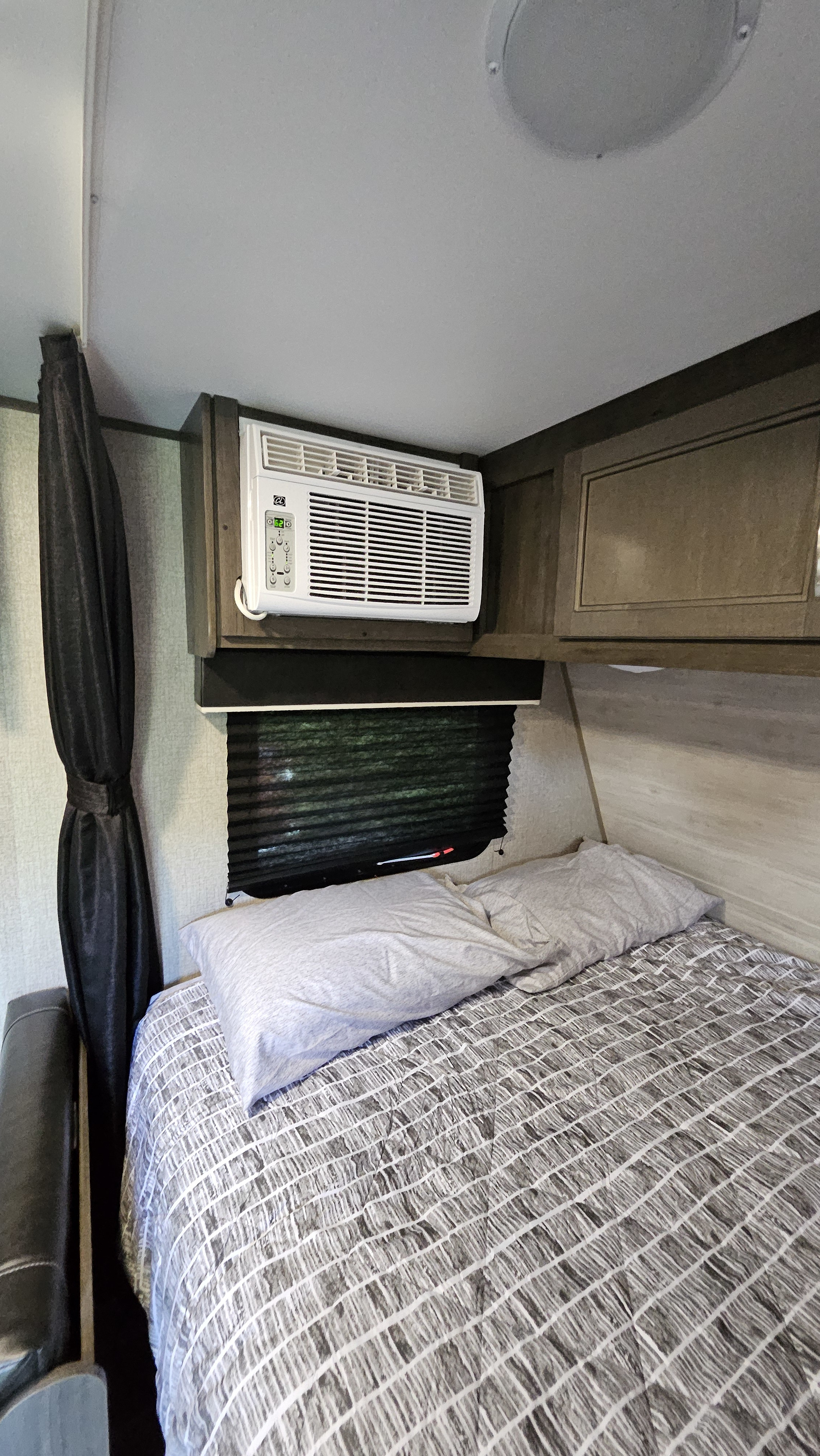 Experience comfort in this RV rental bedroom featuring a wall-mounted AC, a cozy bed, and a window with blinds.. Jayco Jay Flight SLX 2021