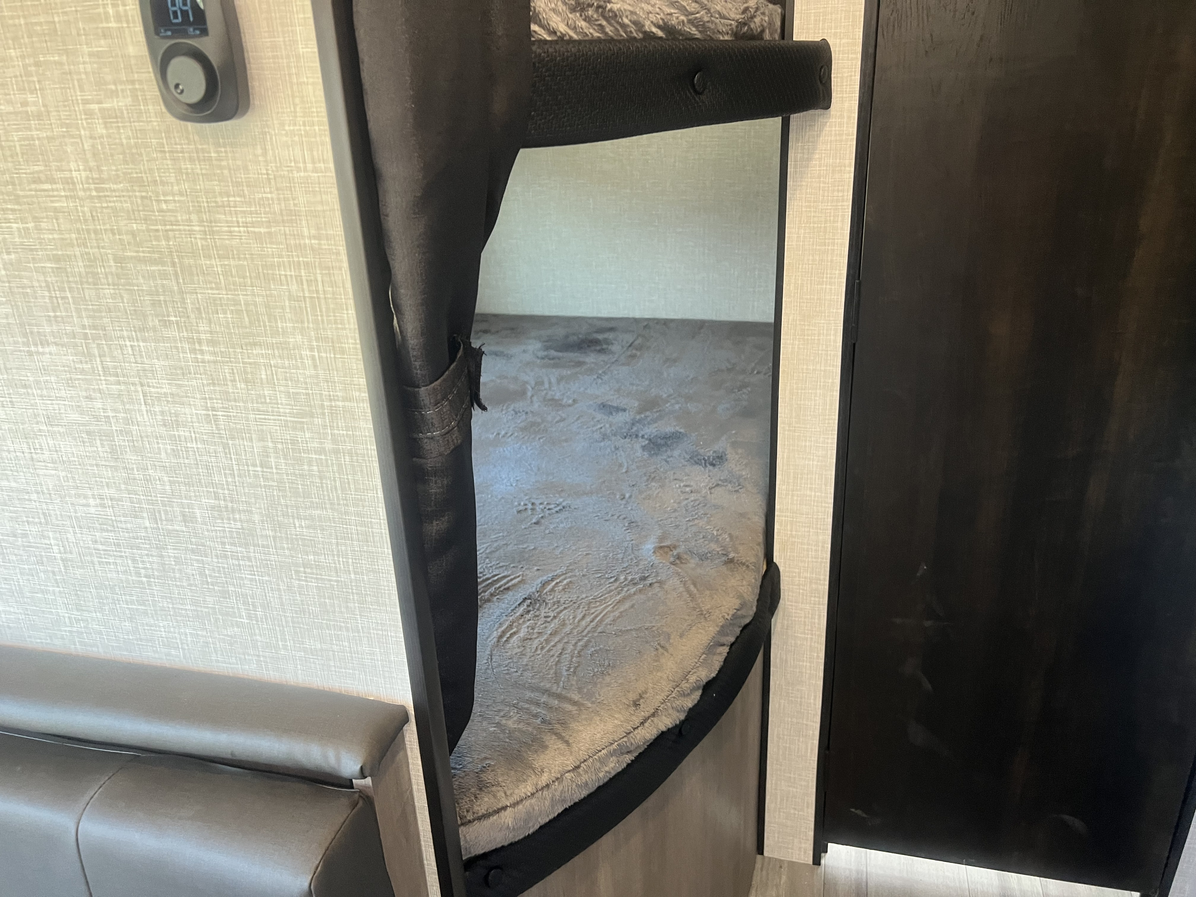 Cozy bunk bed area in an RV rental, featuring a plush blanket and nearby seating for comfort.. Jayco Jay Flight 2024