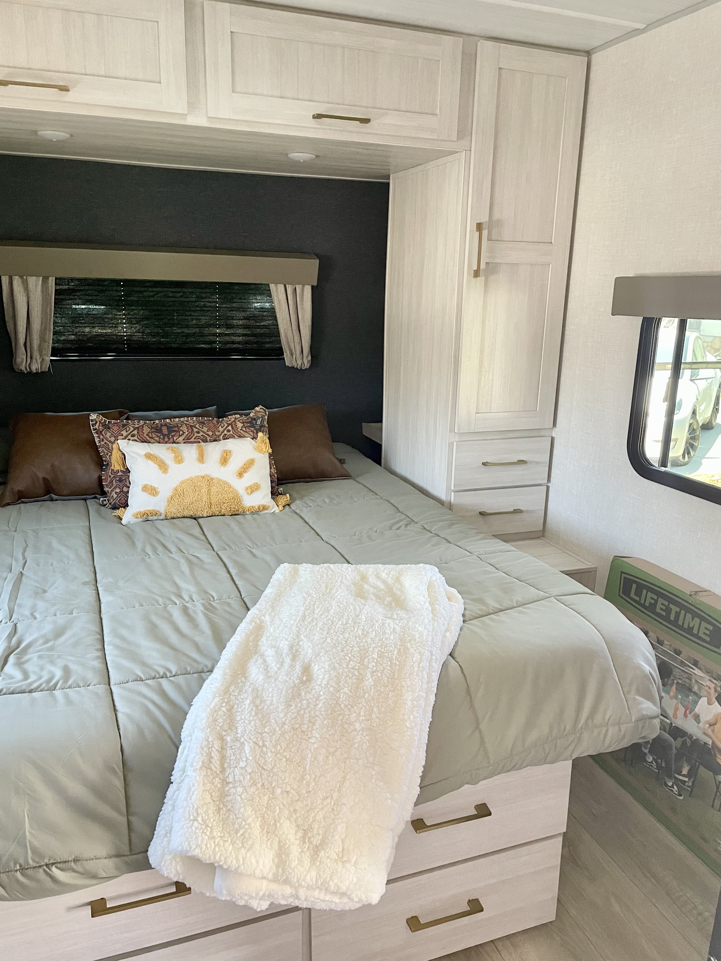 Experience comfort in this RV rental bedroom with light wood finishes, a soft bed, and overhead storage.. Forest River Surveyor Legend 2024