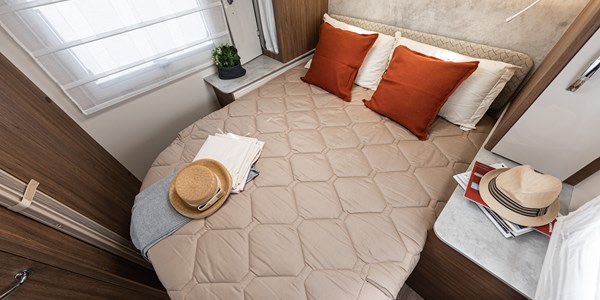 Cozy RV rental bedroom features a comfy bed with pillows, hats, and compact storage. Ideal for travel.. Elnagh 579 2025