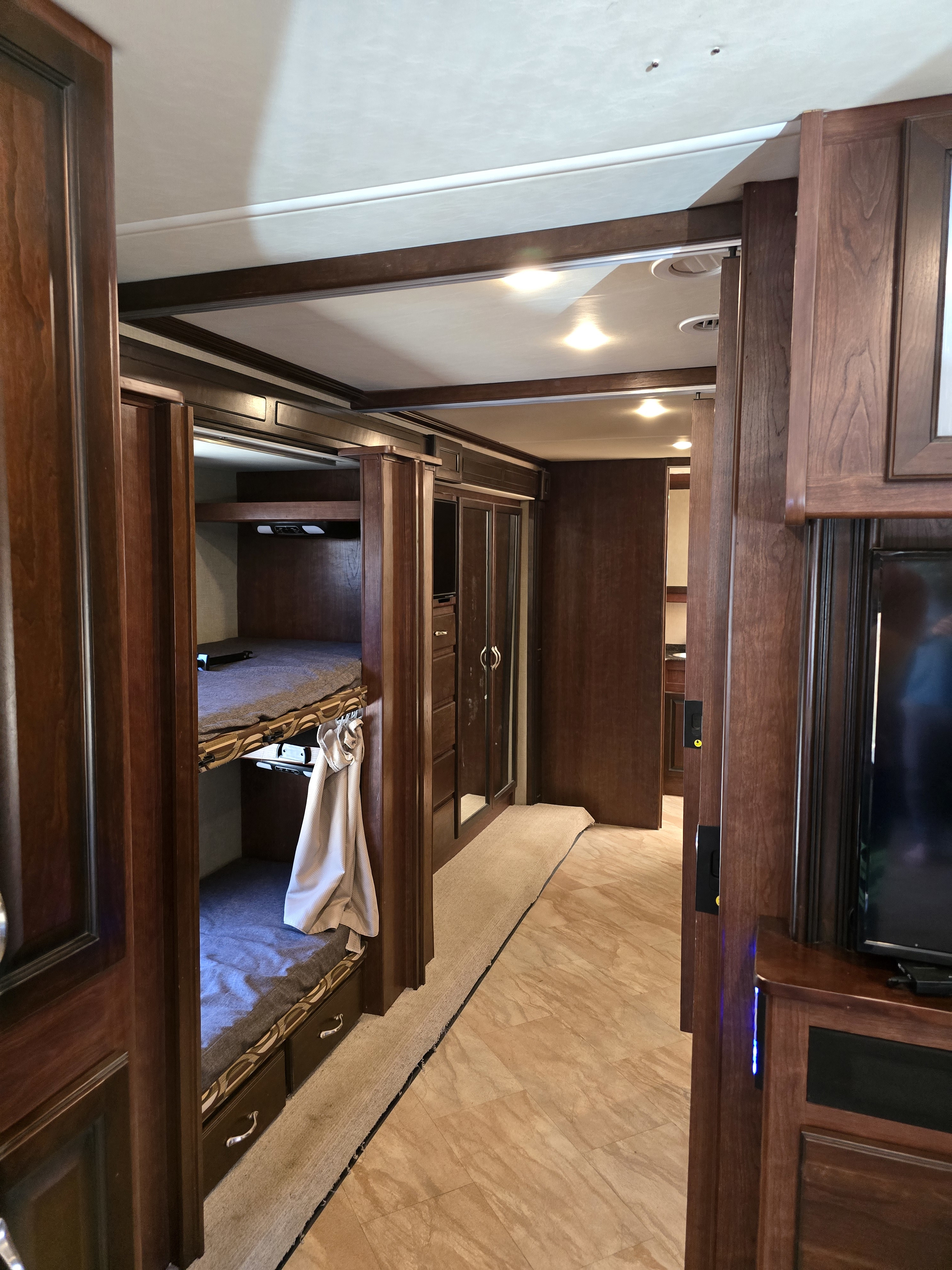 Spacious RV rental interior featuring bunk beds, sleek wood finishes, and a hallway. Perfect for family adventures.. Bounder Bounder Motorhome 2017