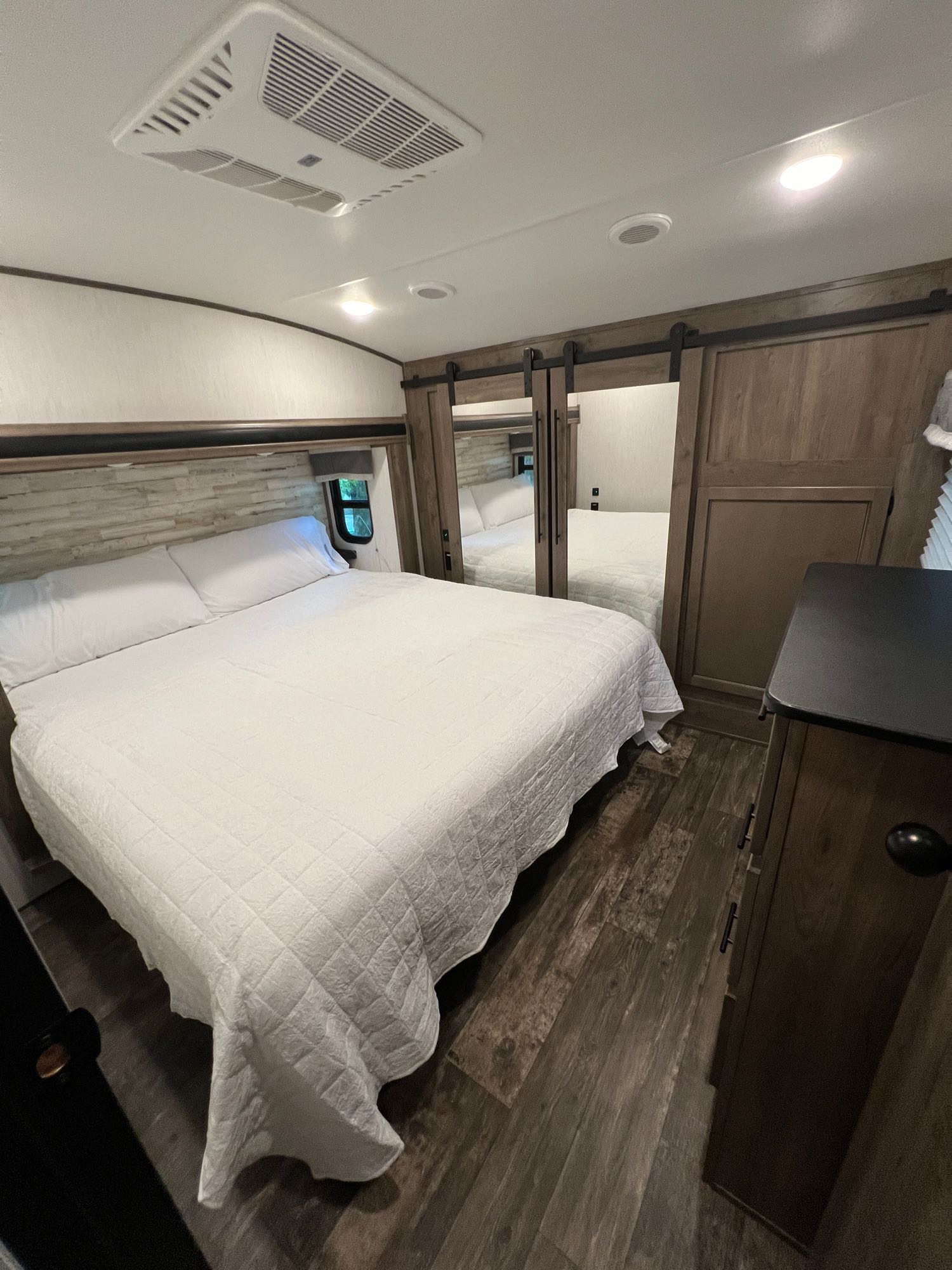 Comfortable RV rental bedroom with a large bed, mirrored sliding closet, and AC unit for a great stay.. Forest River Sabre 2022
