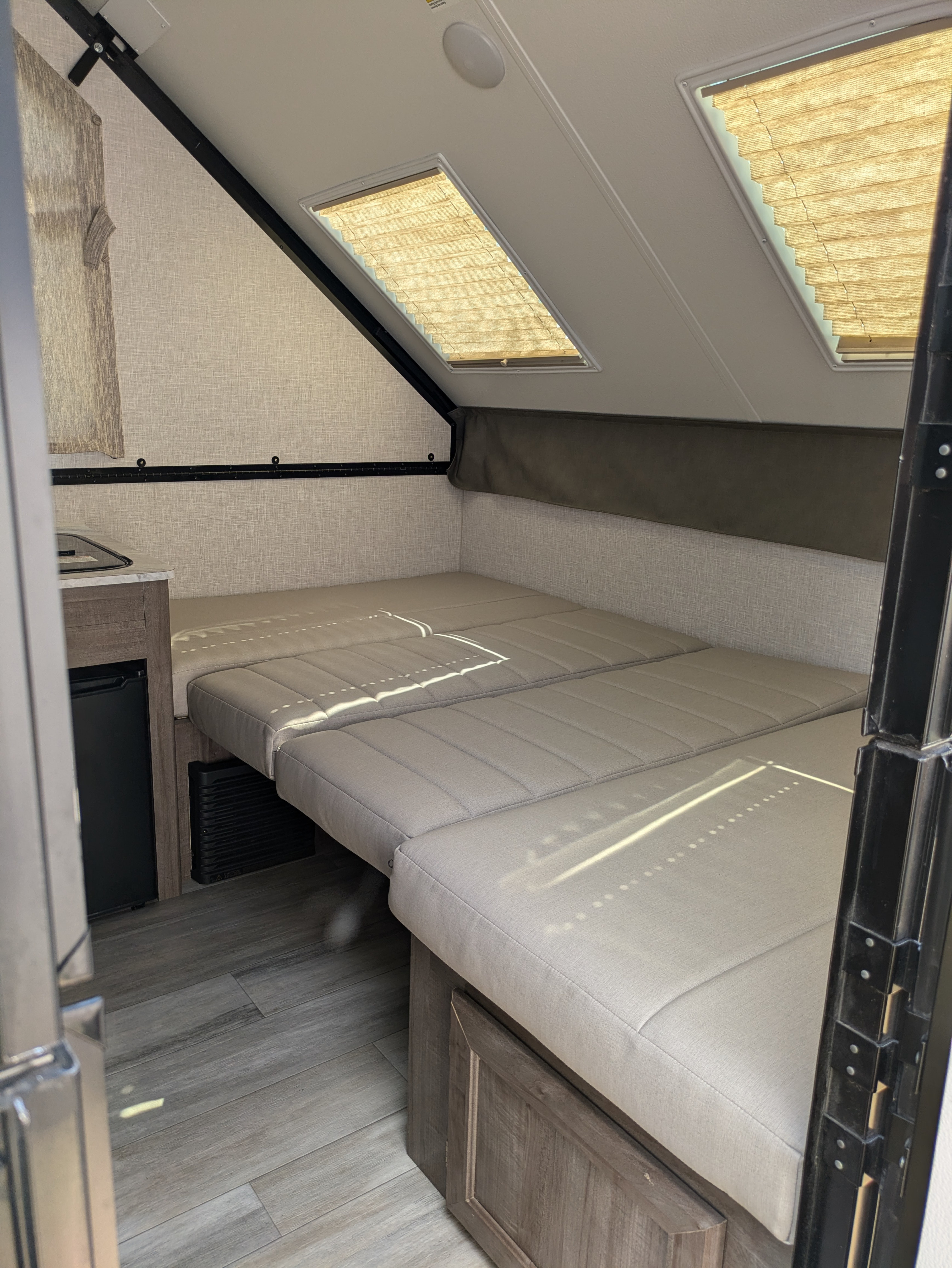 Cozy RV rental interior with a comfortable convertible bed, compact kitchen, and bright skylights, perfect for road trips.. Rockwood A122s 2023