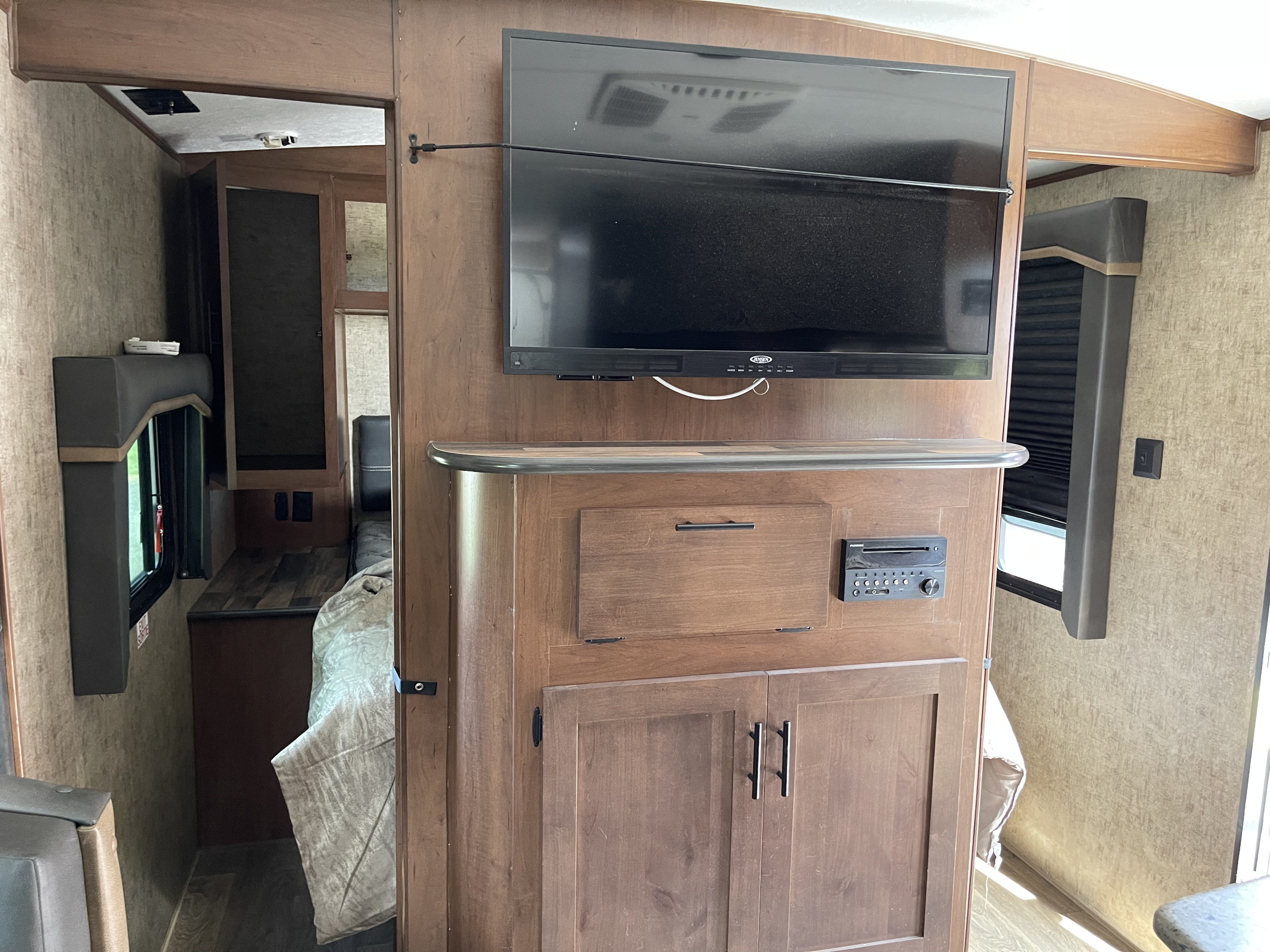 RV rental interior features a wall-mounted TV, integrated audio system, and warm wooden cabinetry in a compact living space.. Outdoors RV Timber Ridge 2021