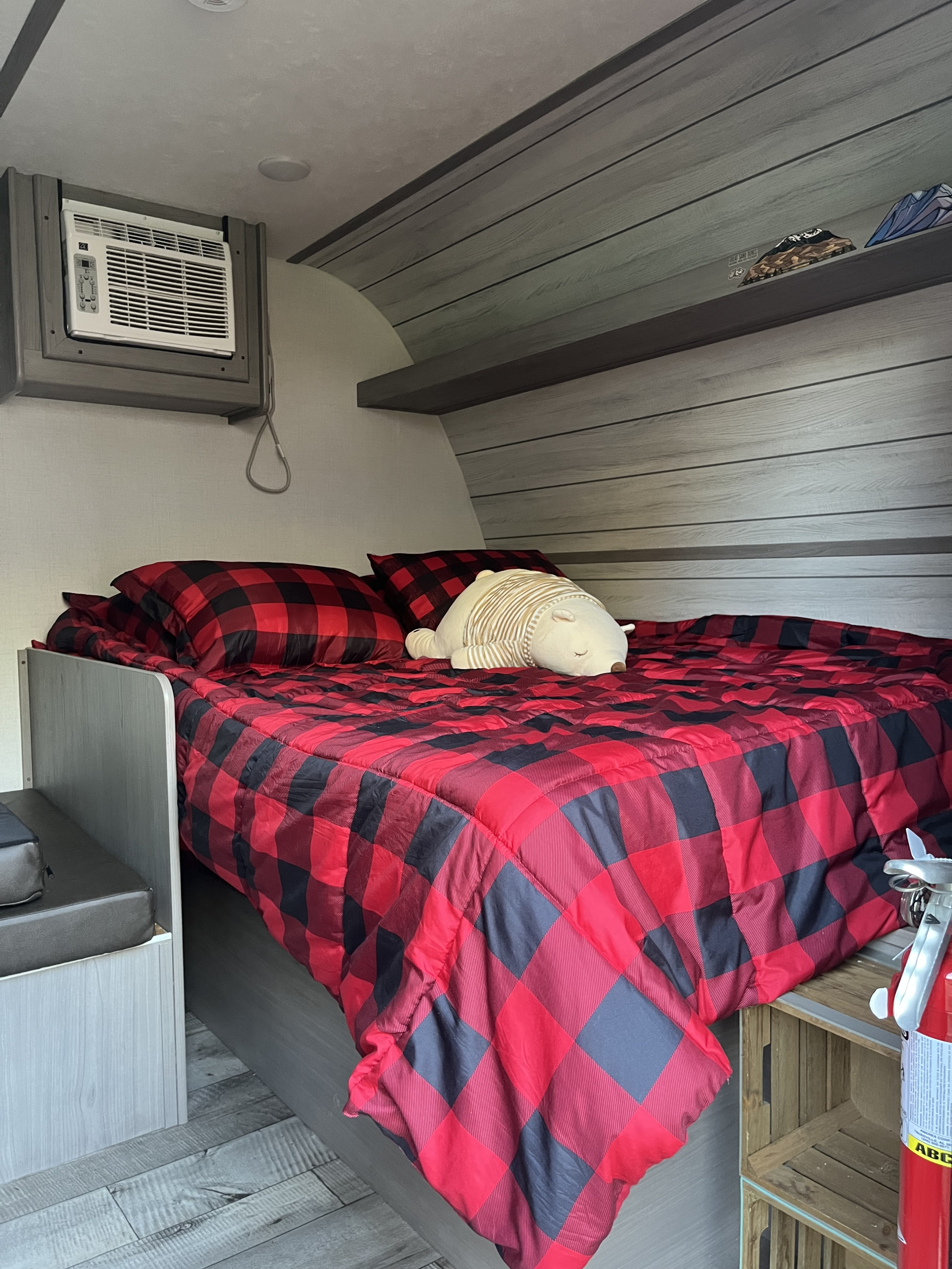 RV rental bedroom: Cozy red plaid bed with a plush bear, AC unit, and modern wood-look walls. Perfect for travel!. COLEMAN LANTERN LT 17B 3990 2024