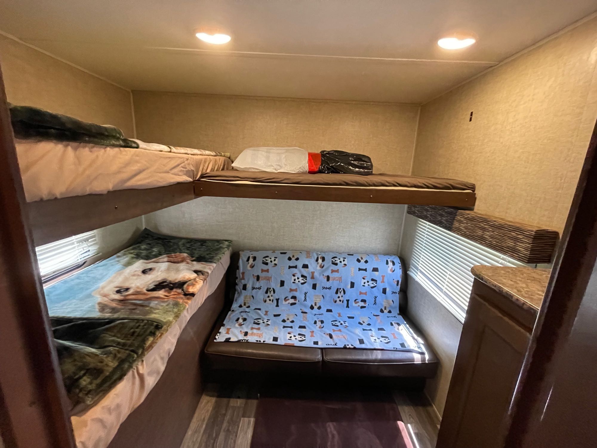 Cozy RV rental interior showcasing bunk beds and a sofa with dog blankets, offering a compact, family-friendly sleeping area.. Keystone RV Hideout Luxury 2016