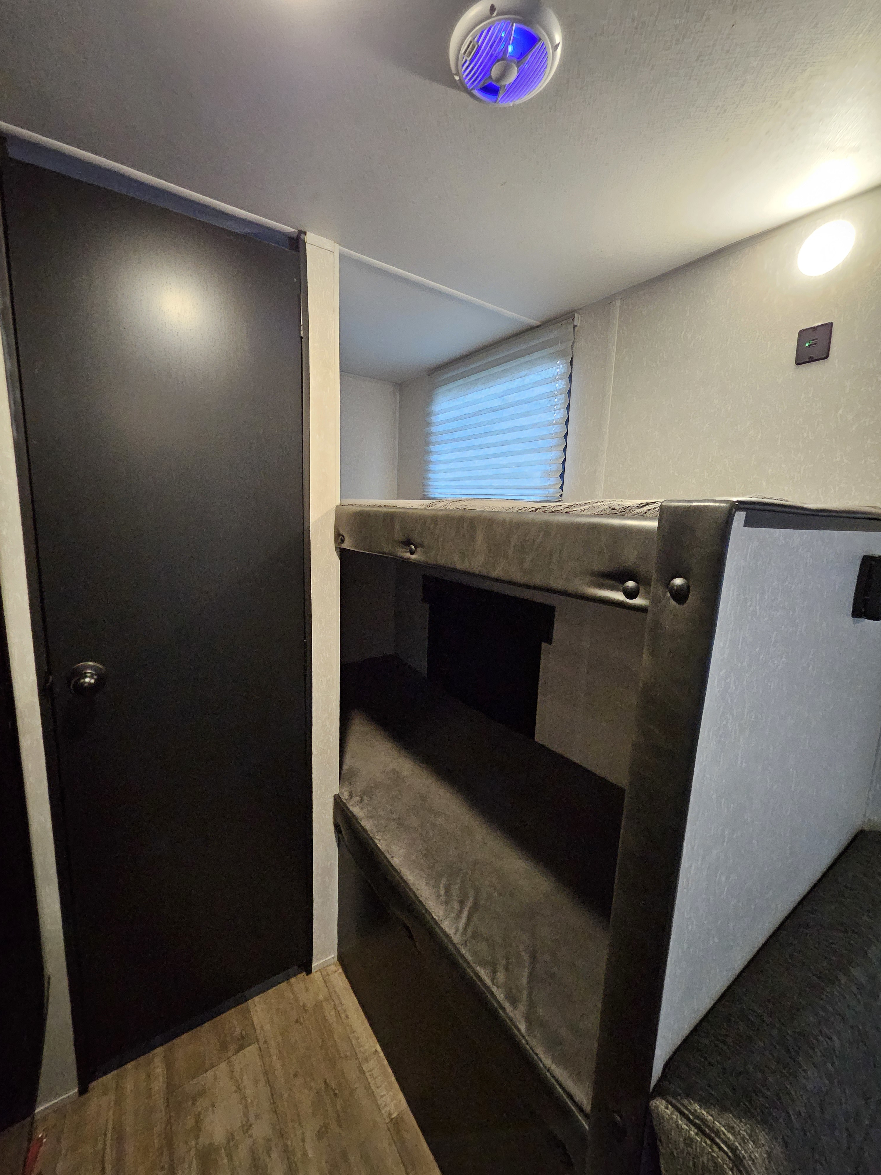 Cozy RV rental interior with comfortable bunk beds, a dark door, and bright lighting, perfect for adventures.. Forest River Cherokee Wolf Pup 2022