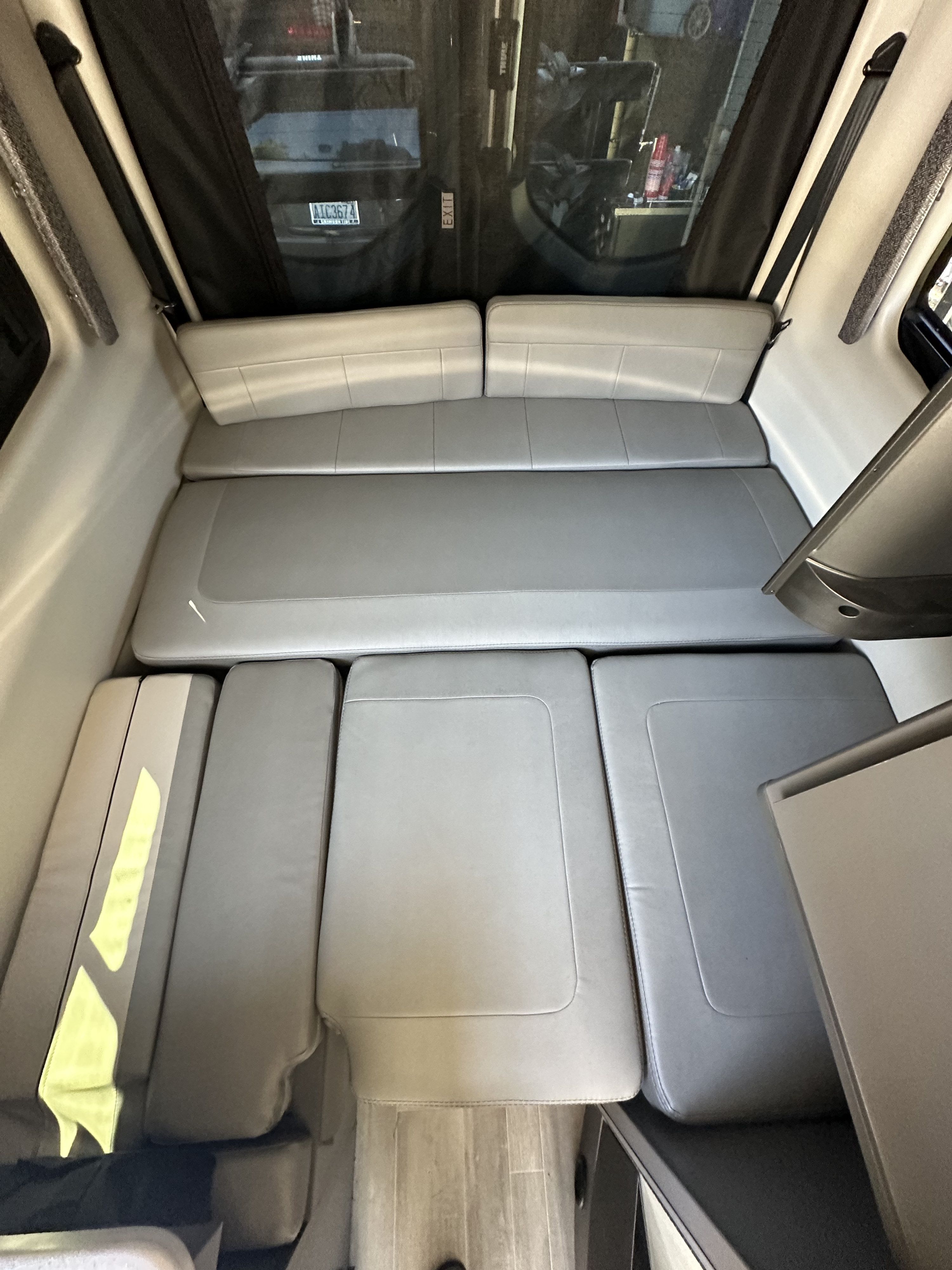 RV rental interior: Versatile grey cushioned seating converts to a bed. Ideal for travel, with exterior view and license plate.. Thor Tranquility 2023