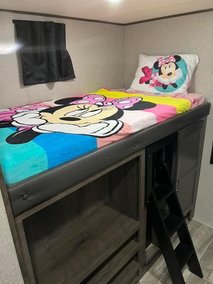 Inside an RV rental: a charming bunk bed with Minnie Mouse bedding, built-in shelves, and a ladder for easy access.. Jayco Jay Flight SLX 2022